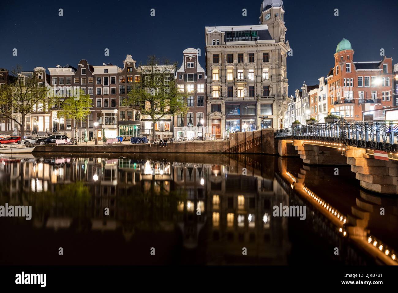 Niederlande, Nordholland, Amsterdam, Stadtkanal bei Nacht mit Molkhäusern im Hintergrund Stockfoto