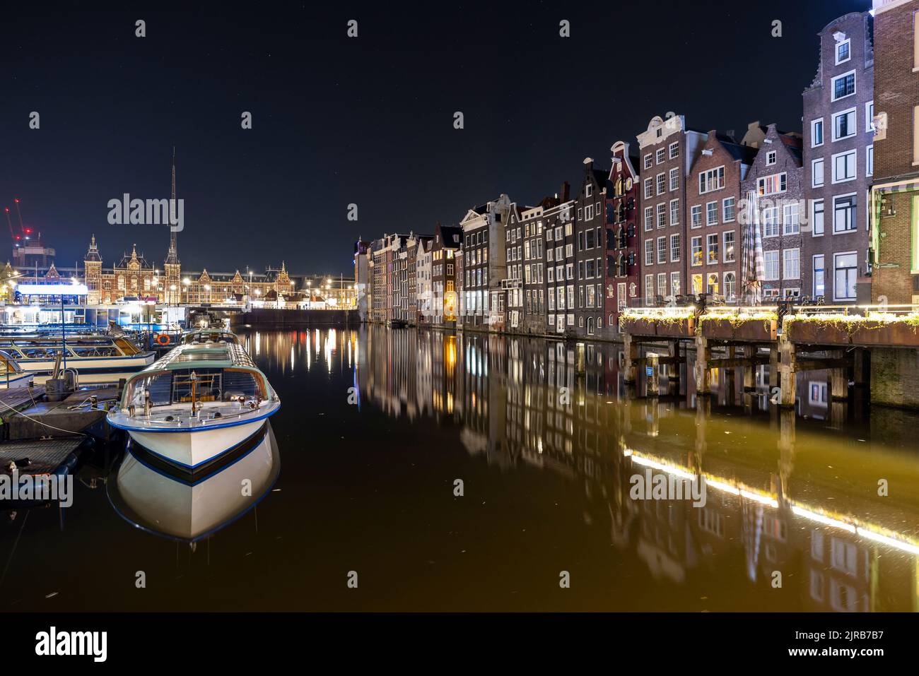 Niederlande, Nordholland, Amsterdam, Langzeitbelichtung des Damrak-Kanals bei Nacht mit Rohhäusern im Hintergrund Stockfoto