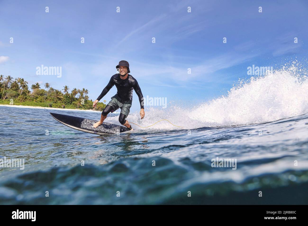 Mann mit Hut beim Surfen im Meer an sonnigen Tagen Stockfoto