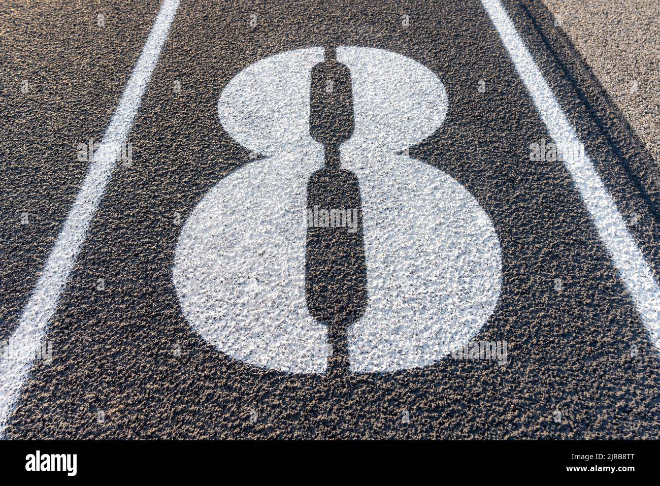 Nahaufnahme der Fahrspur Nr. 8, 8, auf einer neuen schwarzen Laufstrecke mit weißen Fahrspurlinien und anderen Markierungen. Stockfoto