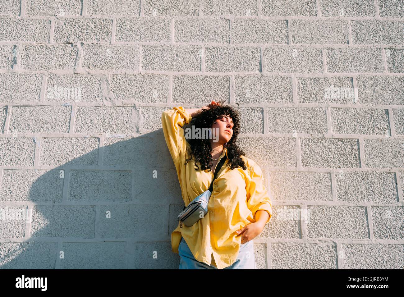 Junge Frau posiert vor Steinmauer Stockfoto