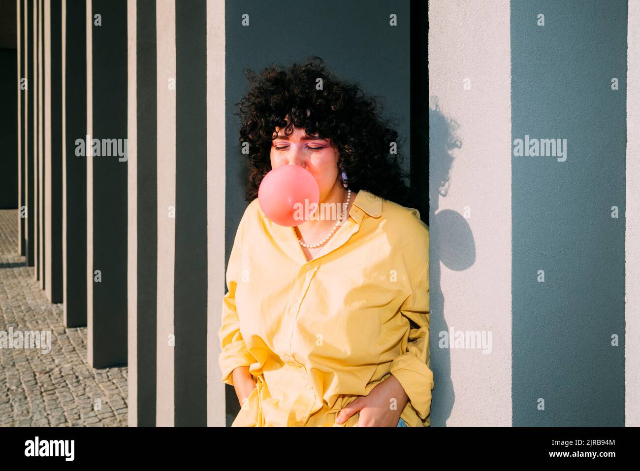 Junge Frau bläst Bubble Gum durch Kolonne Stockfoto