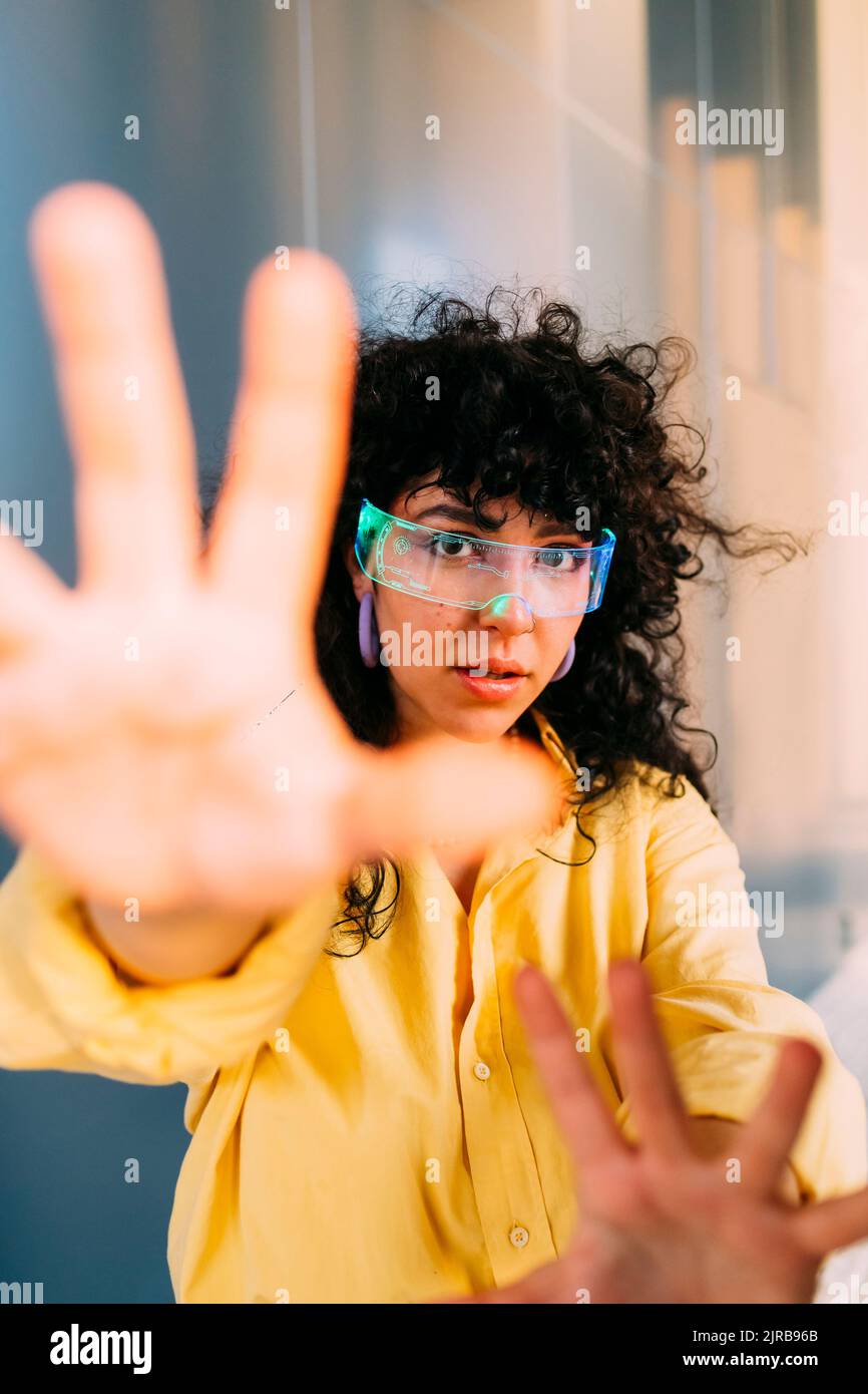 Junge Frau mit Cyber-Brille tut Stop-Geste Stockfoto