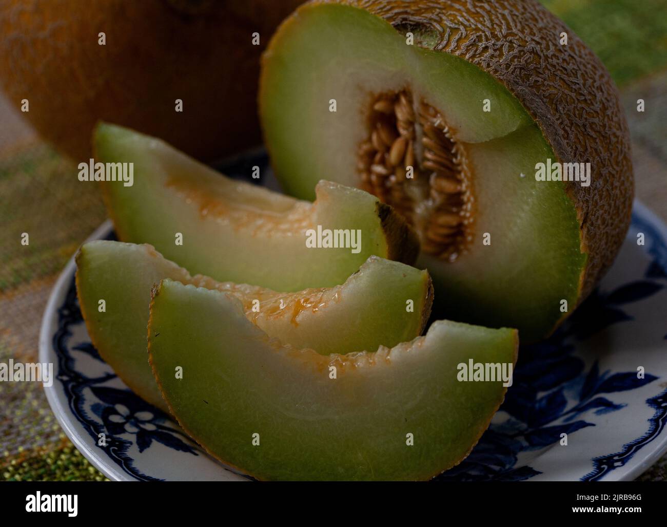 Eine halbe Melone auf einen blauen Teller und ein Loch mit runder Melone daneben schneiden. Stockfoto