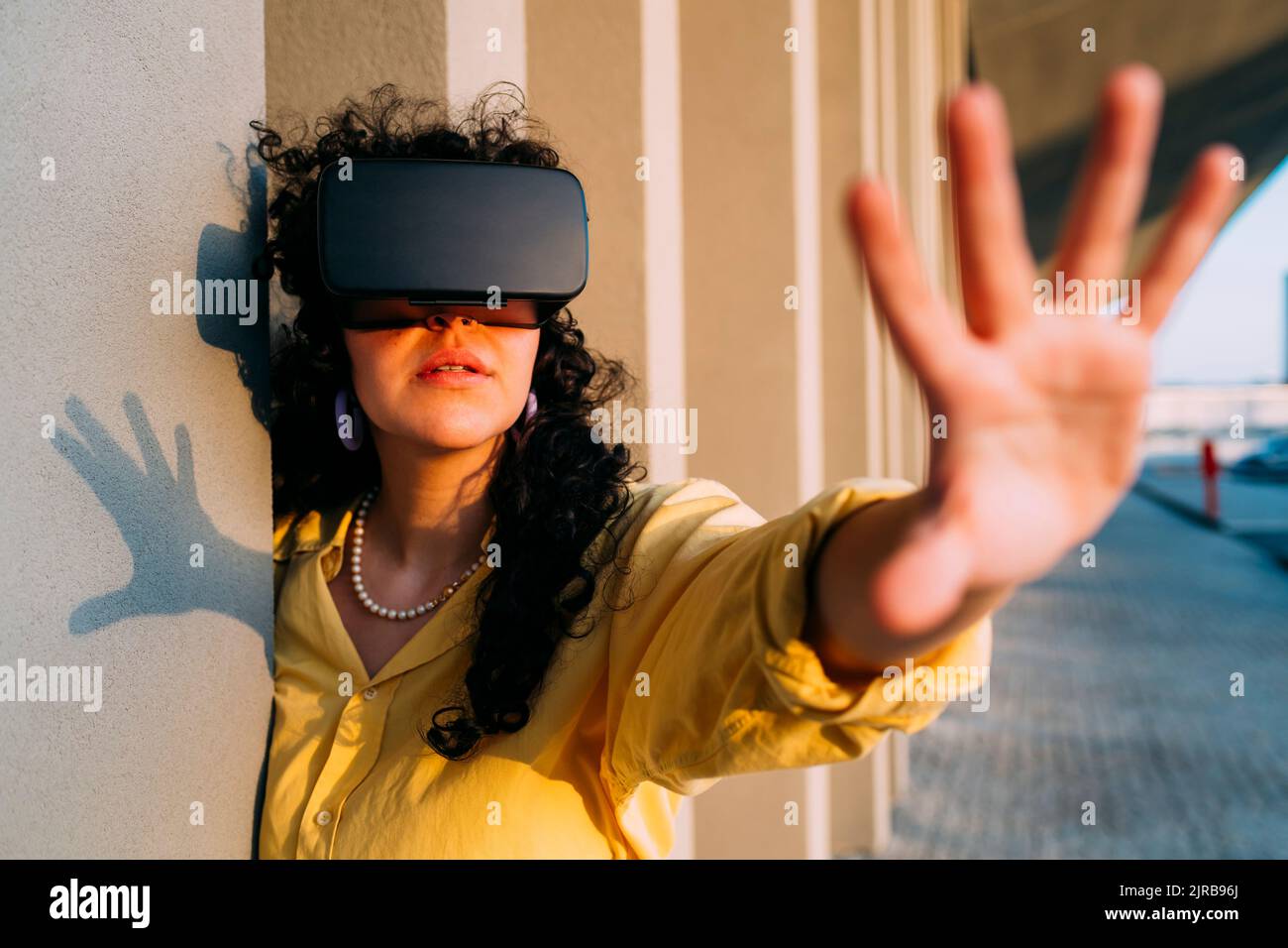 Junge Frau mit VR-Brille tut Stop-Geste von Spalte Stockfoto