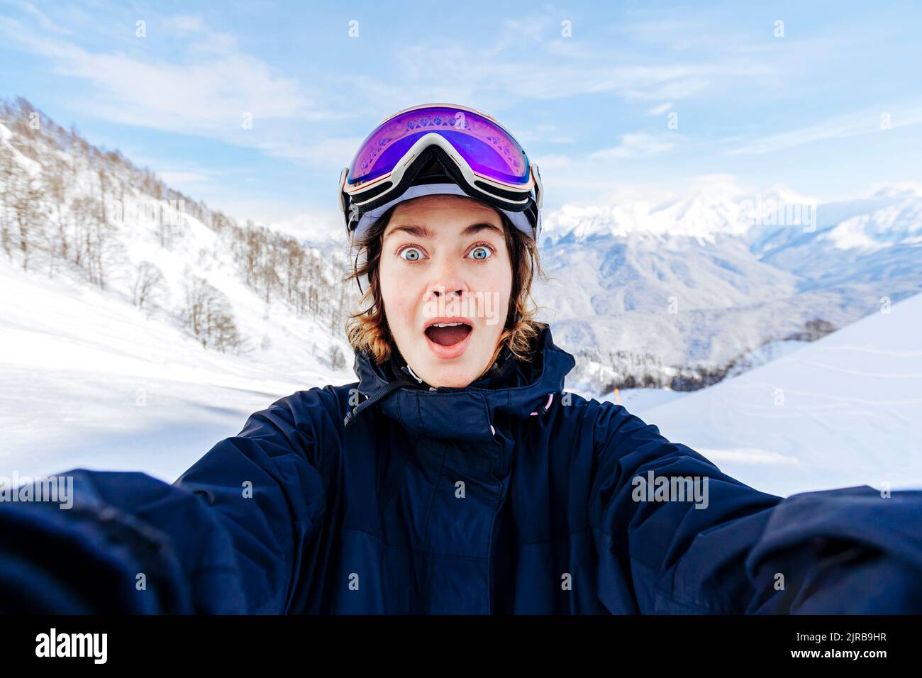 Schockierte Frau mit offenem Mund vor verschneiten Bergen Stockfoto
