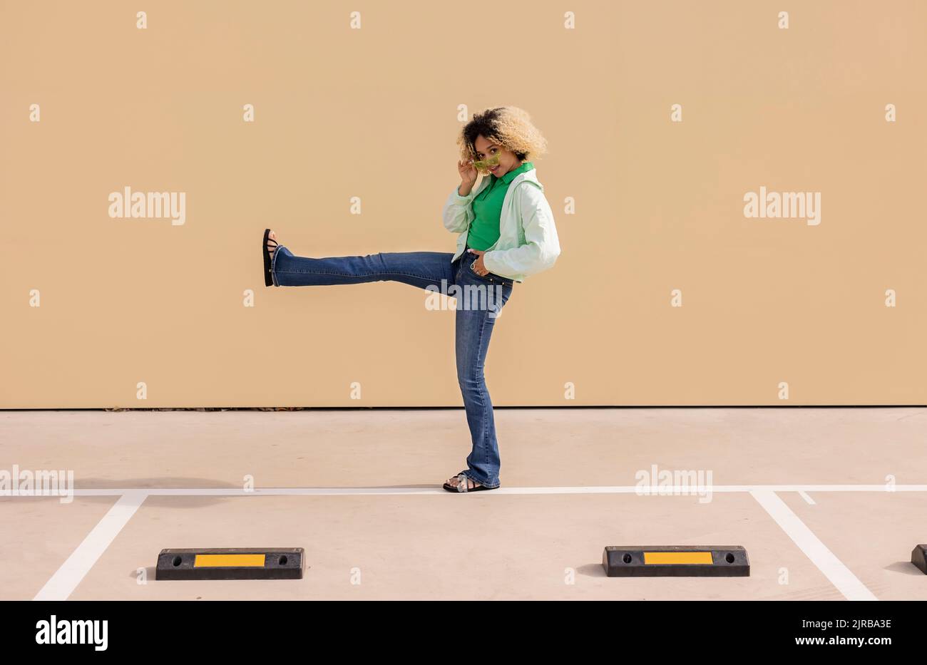 Junge Frau, die auf einem Bein vor der Wand steht Stockfoto