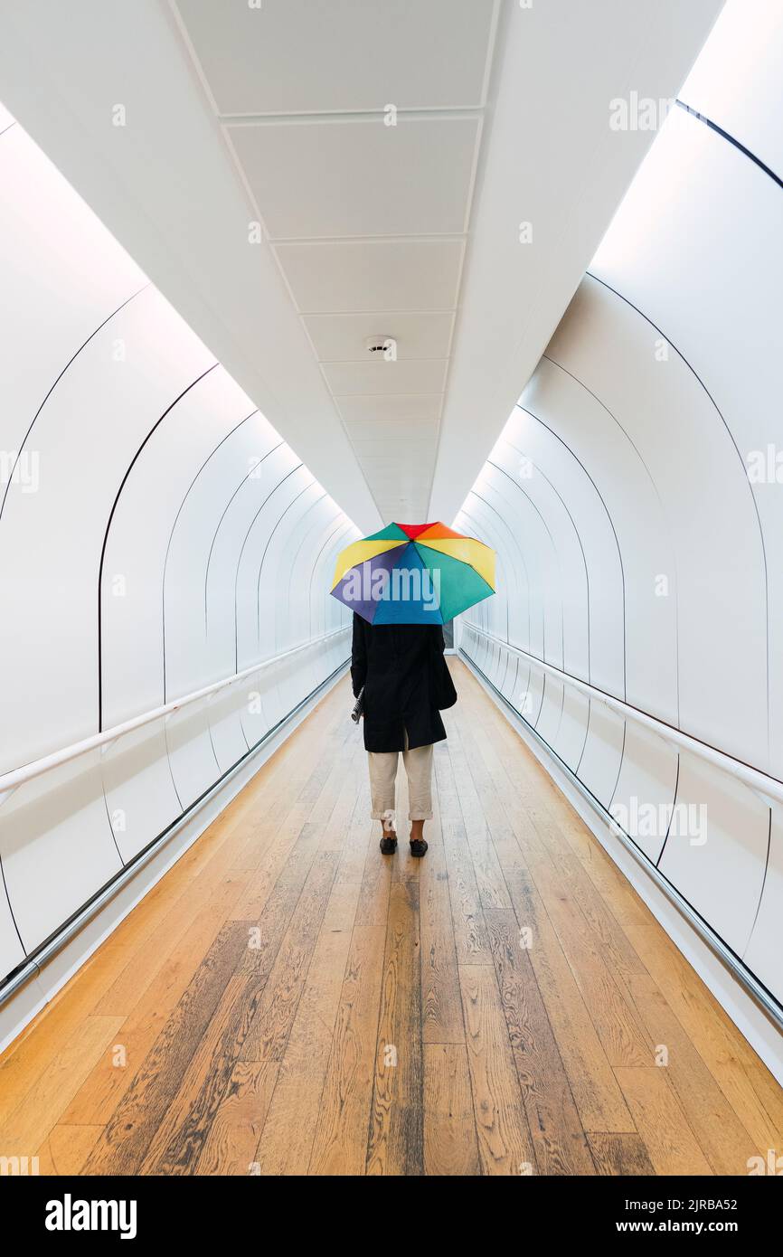 Frau mit Regenschirm, der auf dem Gehweg steht Stockfoto