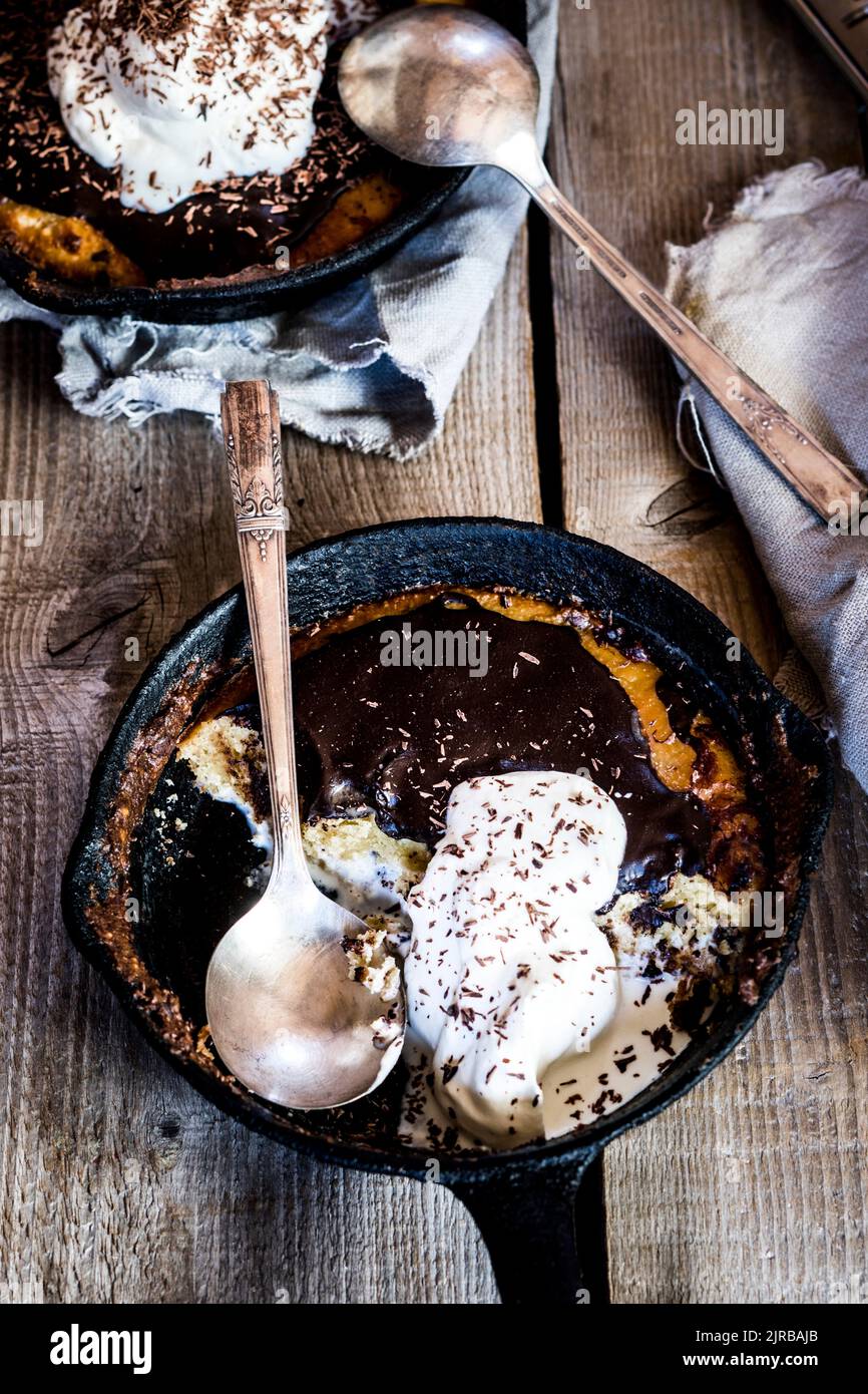 Bratpfannen mit Schokoladenstückchen, überzogen mit Ganache-Belag und Schlagsahne Stockfoto