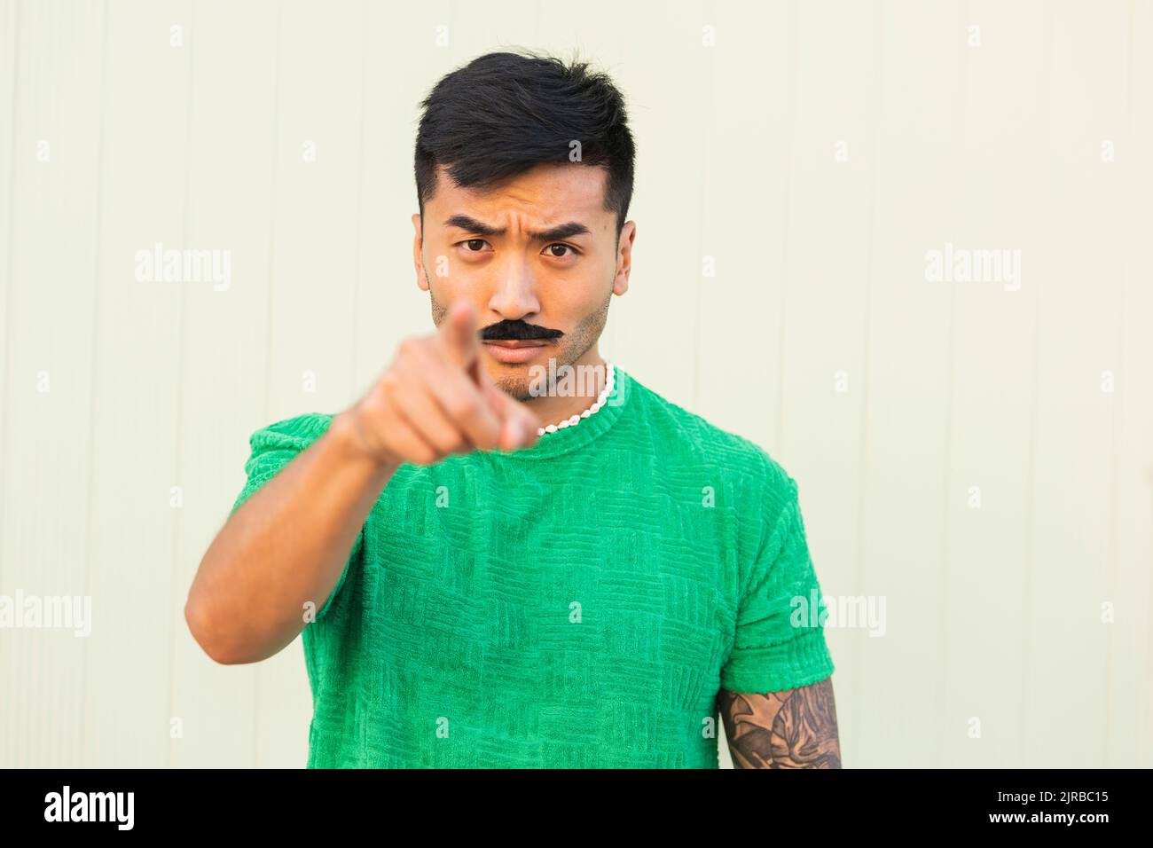 Junger Mann mit ernstem Ausdruck, der vor die Wand zeigt Stockfoto