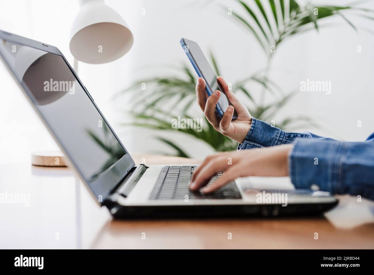 Hände einer Geschäftsfrau, die drahtlose Technologien im Heimbüro nutzt Stockfoto