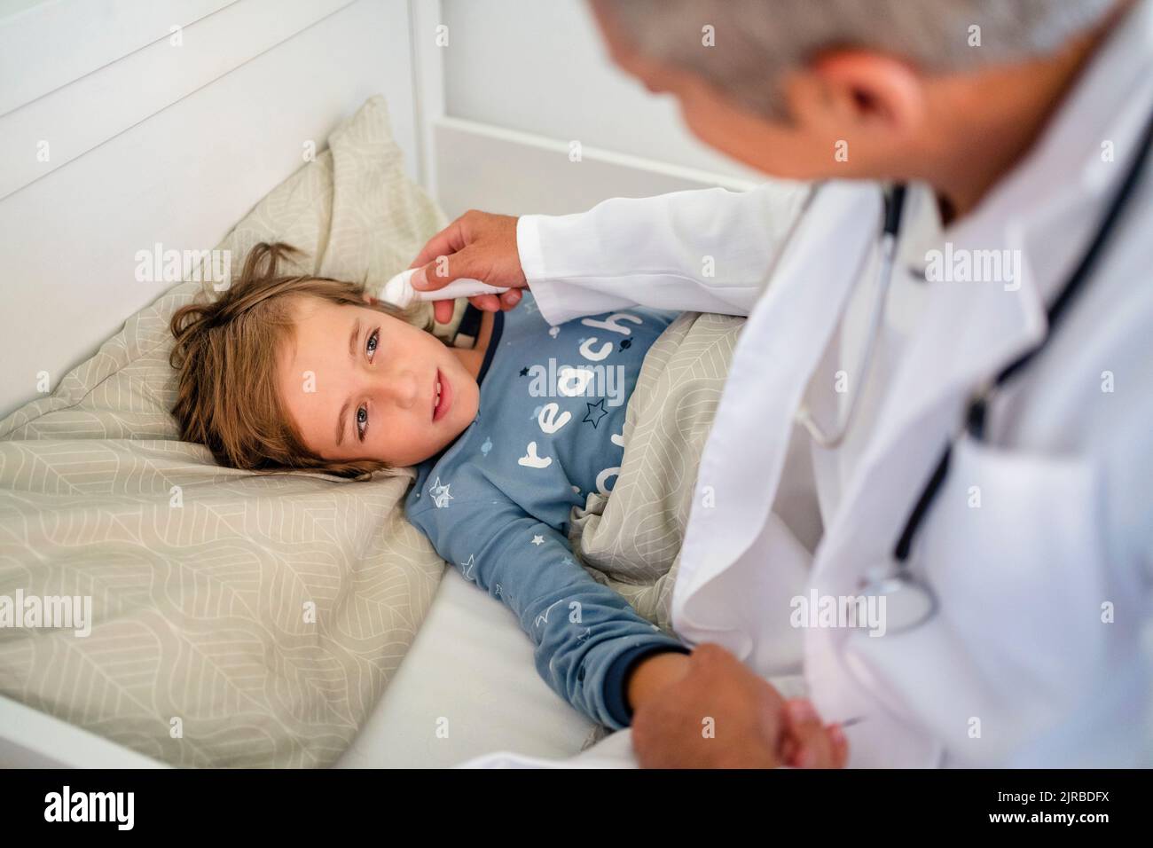 Arzt untersucht Jungen im Bett zu Hause Stockfoto