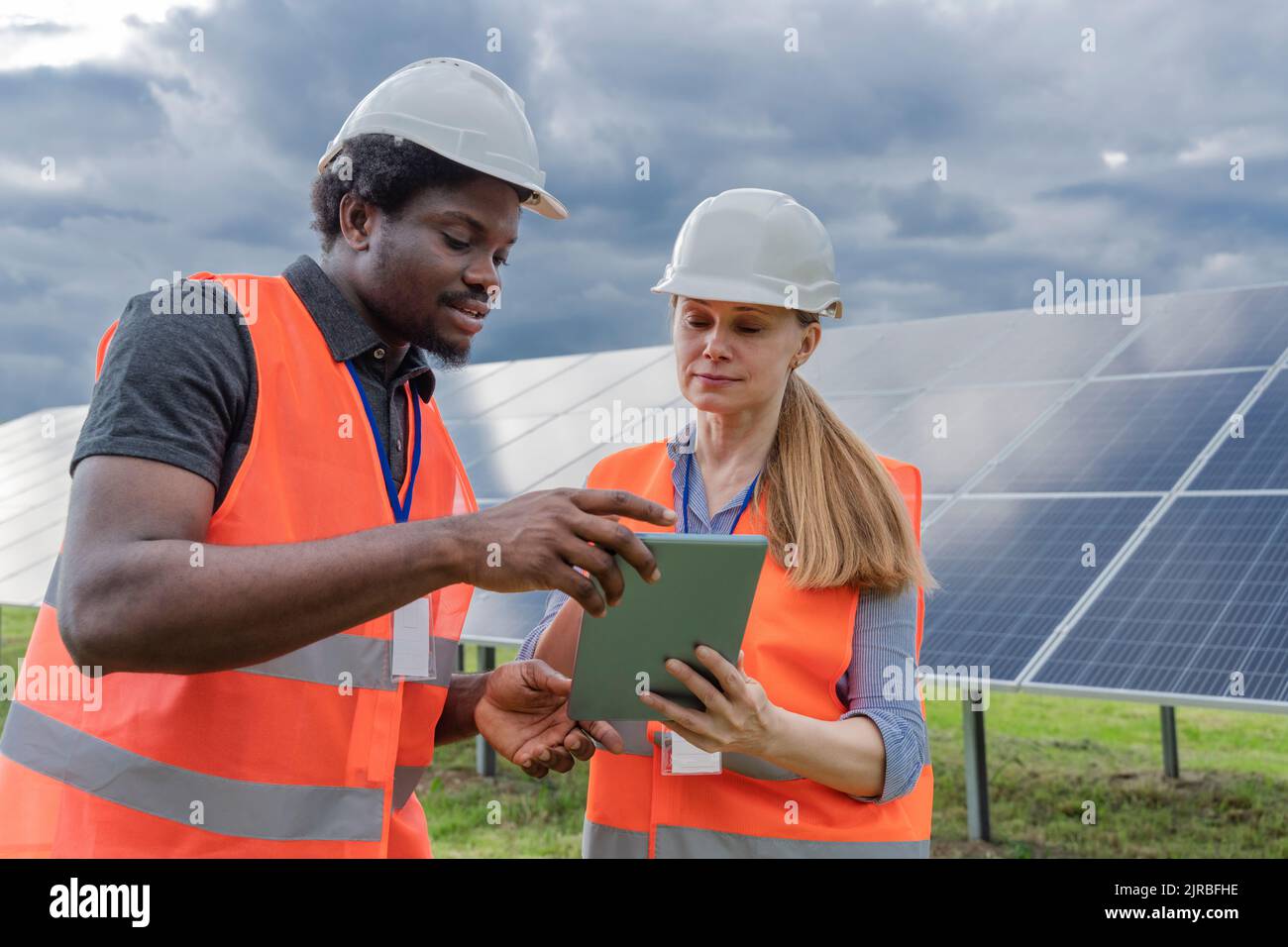Techniker und Mitarbeiter teilen sich einen Tablet-PC an einer Solarstation Stockfoto