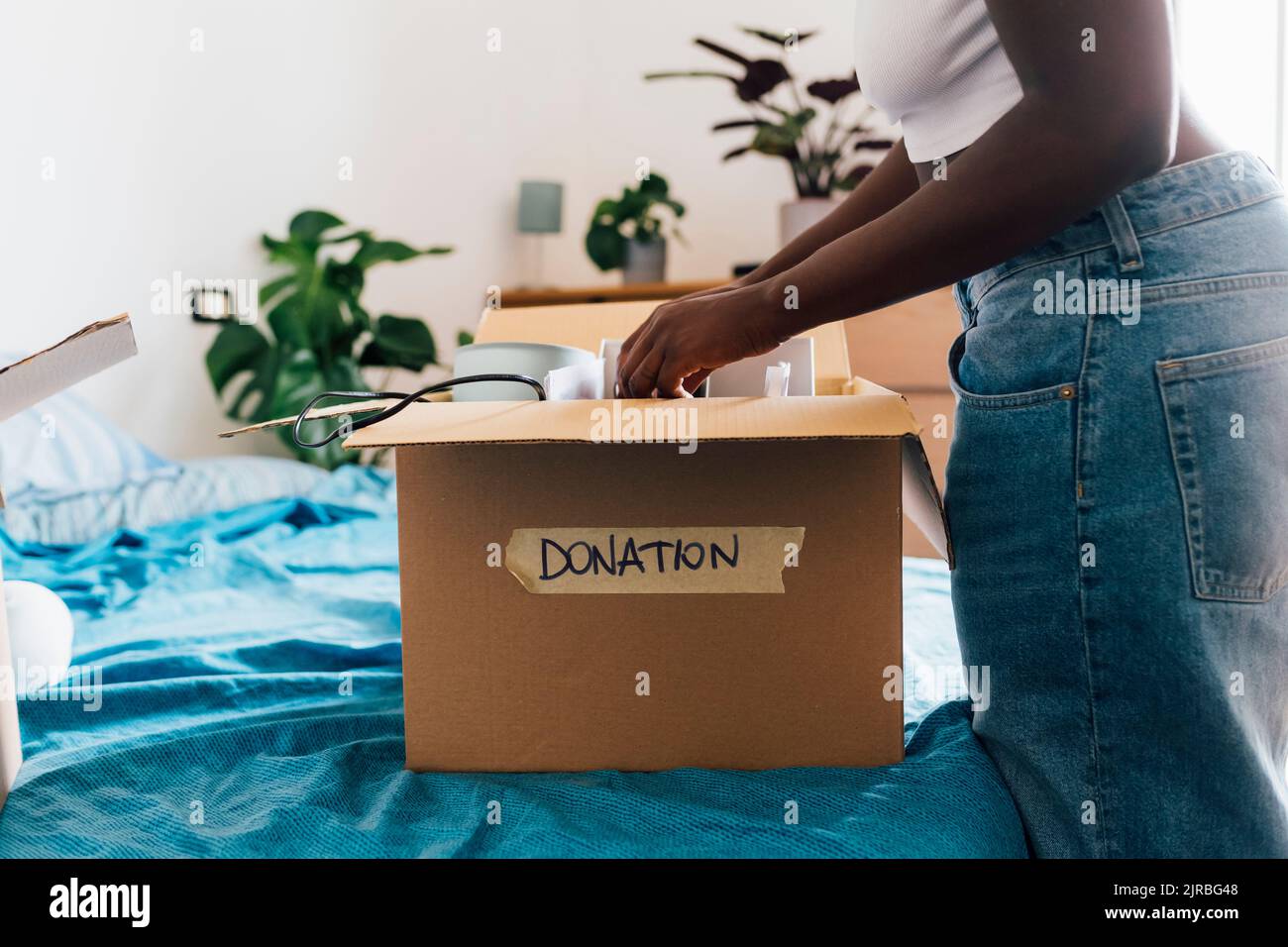 Frau, die zu Hause eine Spendenbox auf das Bett packt Stockfoto