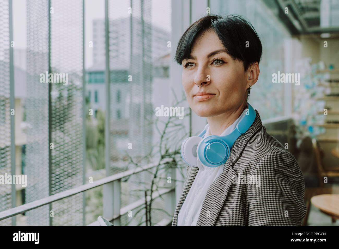 Durchdachte Geschäftsfrau mit kurzen Haaren und kabellosen Kopfhörern Stockfoto