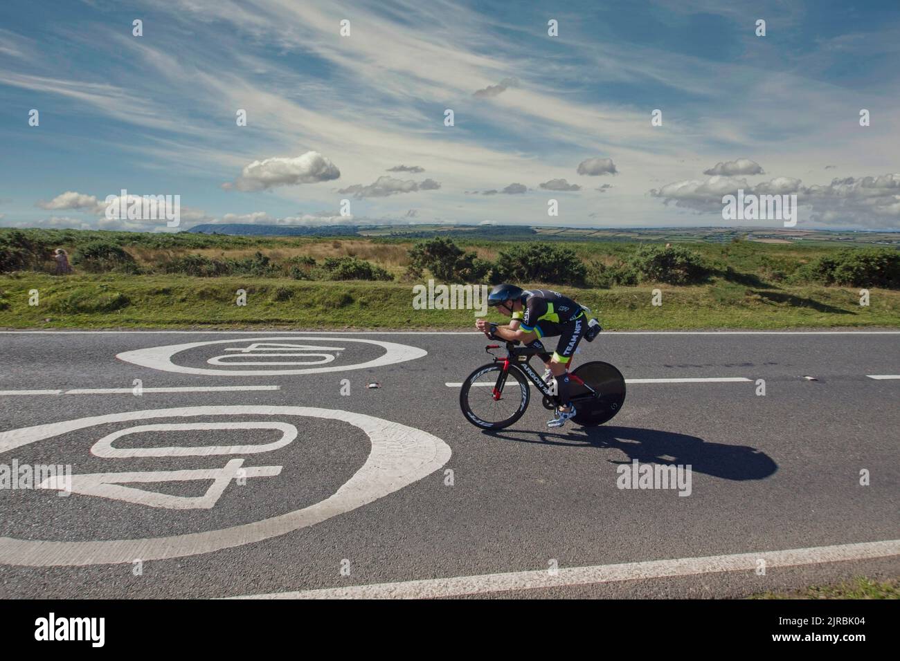 7. August 22 Gower Swansea Wales UK Triathlon Ironman Radsportler nähern sich der Straße mit gemaltem „40“-Schild zur Geschwindigkeitsbegrenzung in Richtung rechts nach links Stockfoto