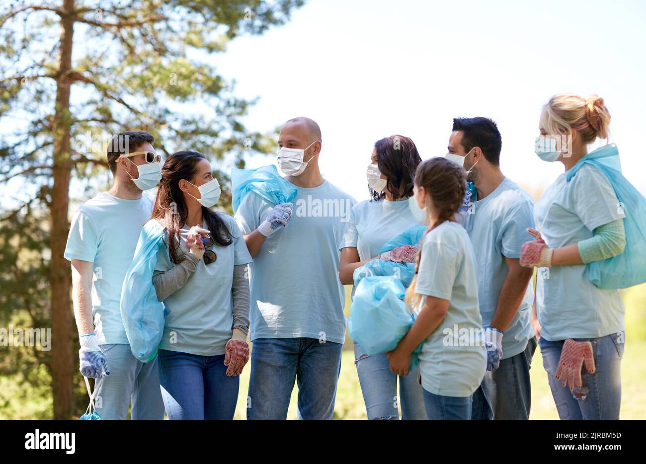 Freiwillige in Masken mit Mülltüten reden Stockfoto