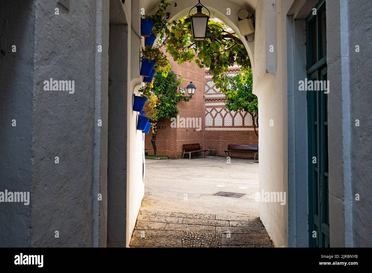 Traditionelle kleine Gasse im spanisch-andalusischen Stil mit blauen Töpfen und malerischem Tageslicht. Klassische spanische Kleinstadt mit weißen Wänden Stockfoto