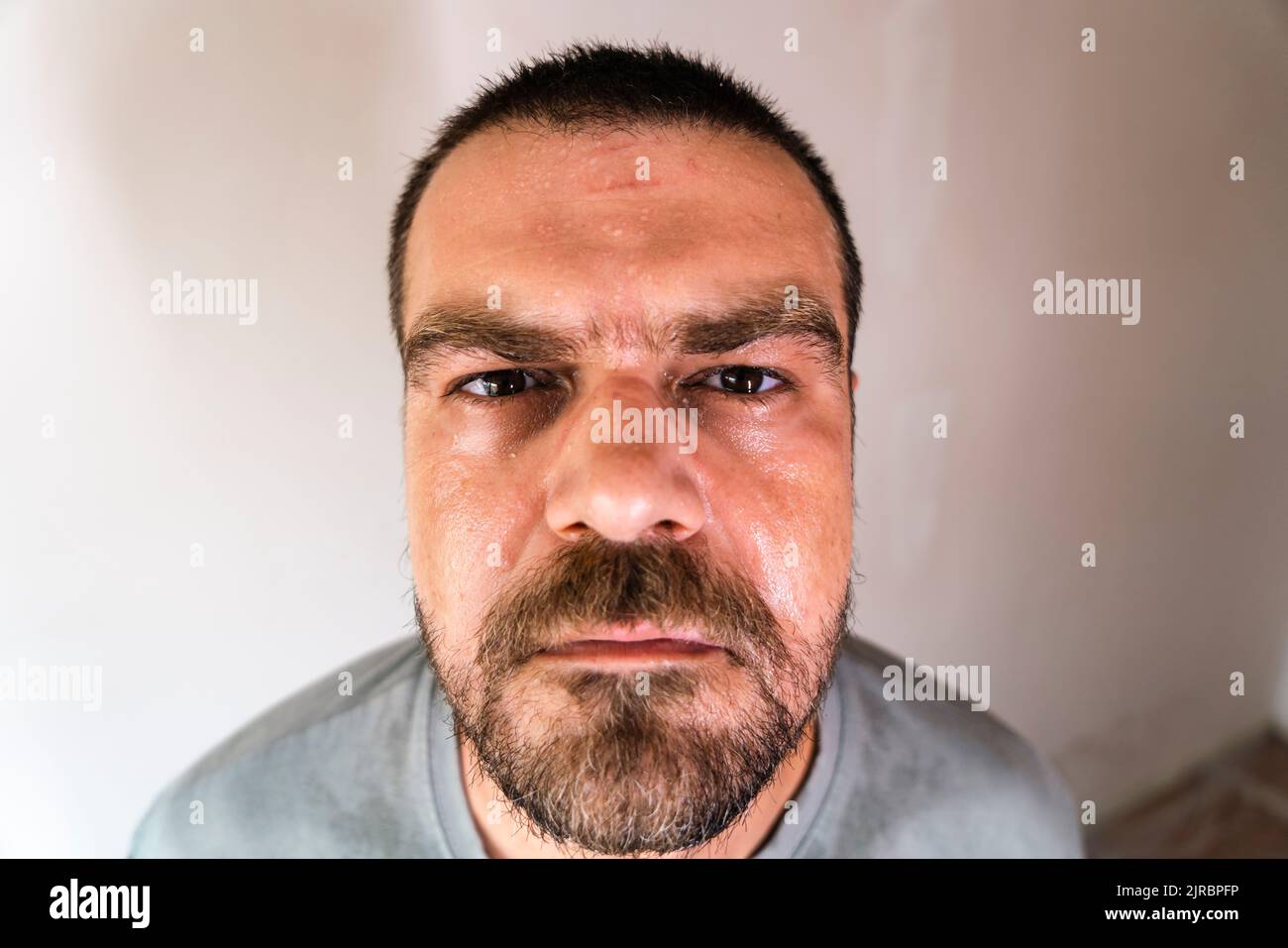 Selektiver Fokus, Nahaufnahme, Weitwinkelaufnahme eines kaukasischen bärtigen Mannes mit verschwitztem Gesicht. Stockfoto