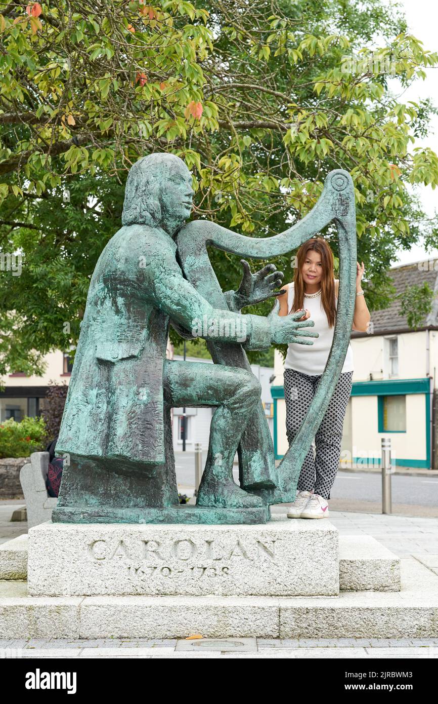 Eine Dame posiert bei einer Statue einer irischen Harfenistin in Irland. Stockfoto