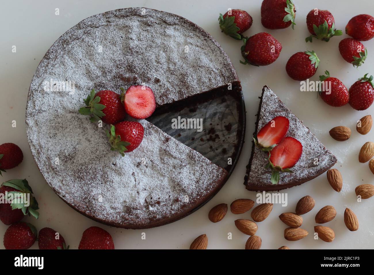 Tortenkaprese in Scheiben. Schokolade- und Mandelkuchen. Ein leckerer, schokoladiger, mehlloser Kuchen von der italienischen Insel Capri. Mit Zuckerpulver bestreut. Stockfoto