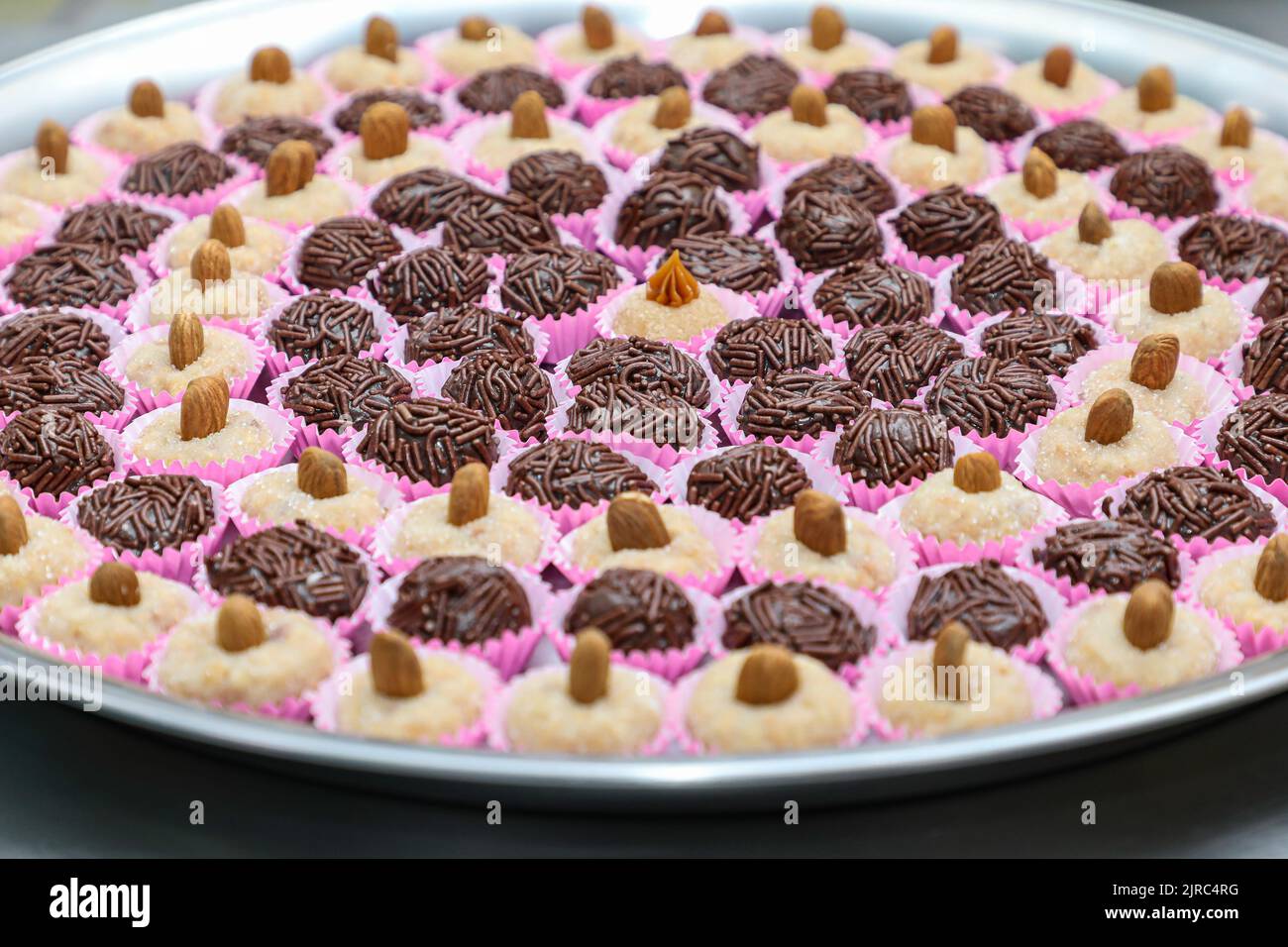 Tablett mit Brigadieren und Cashews in einer kreisförmigen Form in einer Form, in der Mitte eine andere süße mit Dulce de leche auf der Oberseite geteilt. Stockfoto