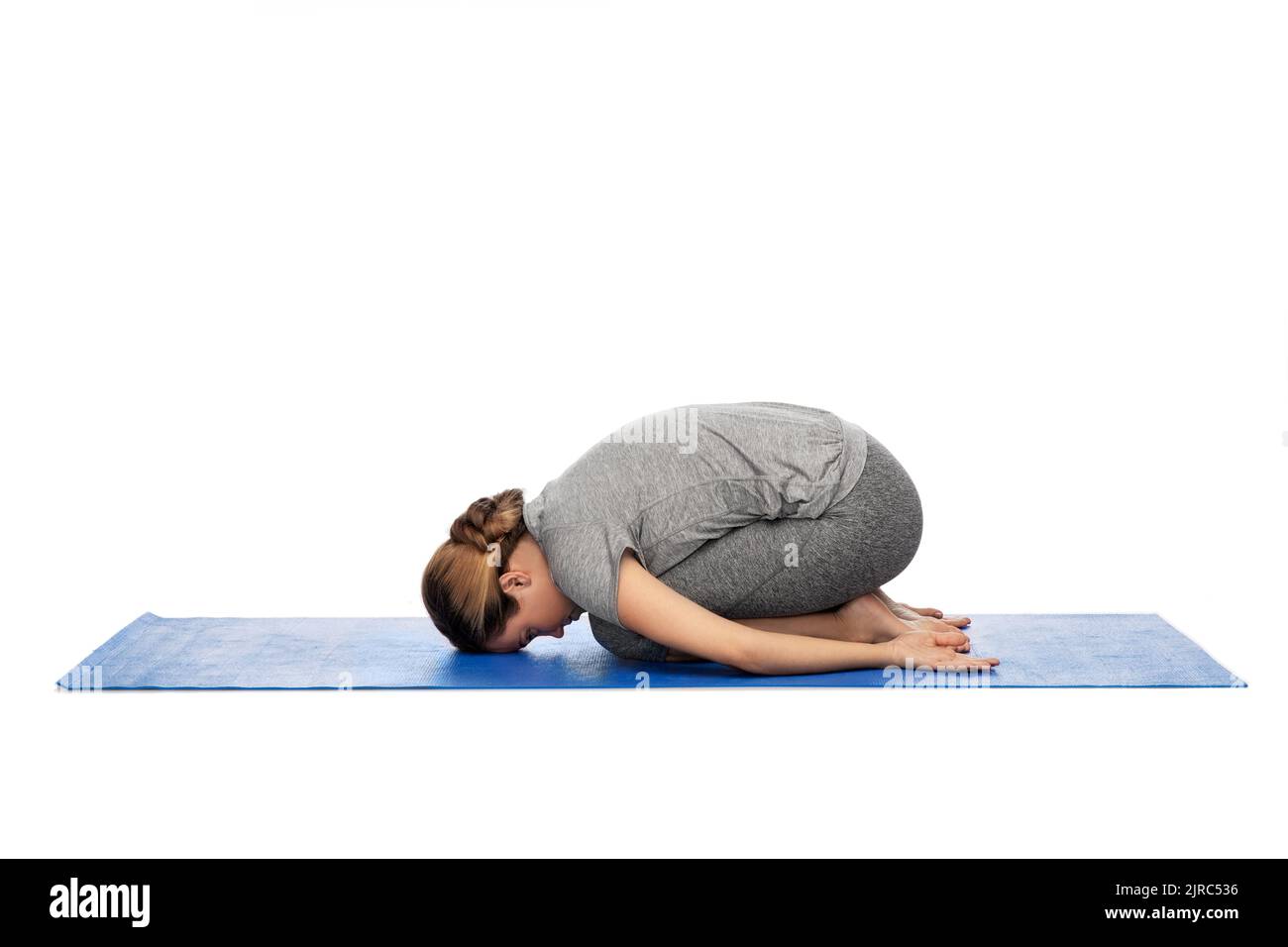 Frau tut Yoga Kind Pose auf Matte Stockfoto