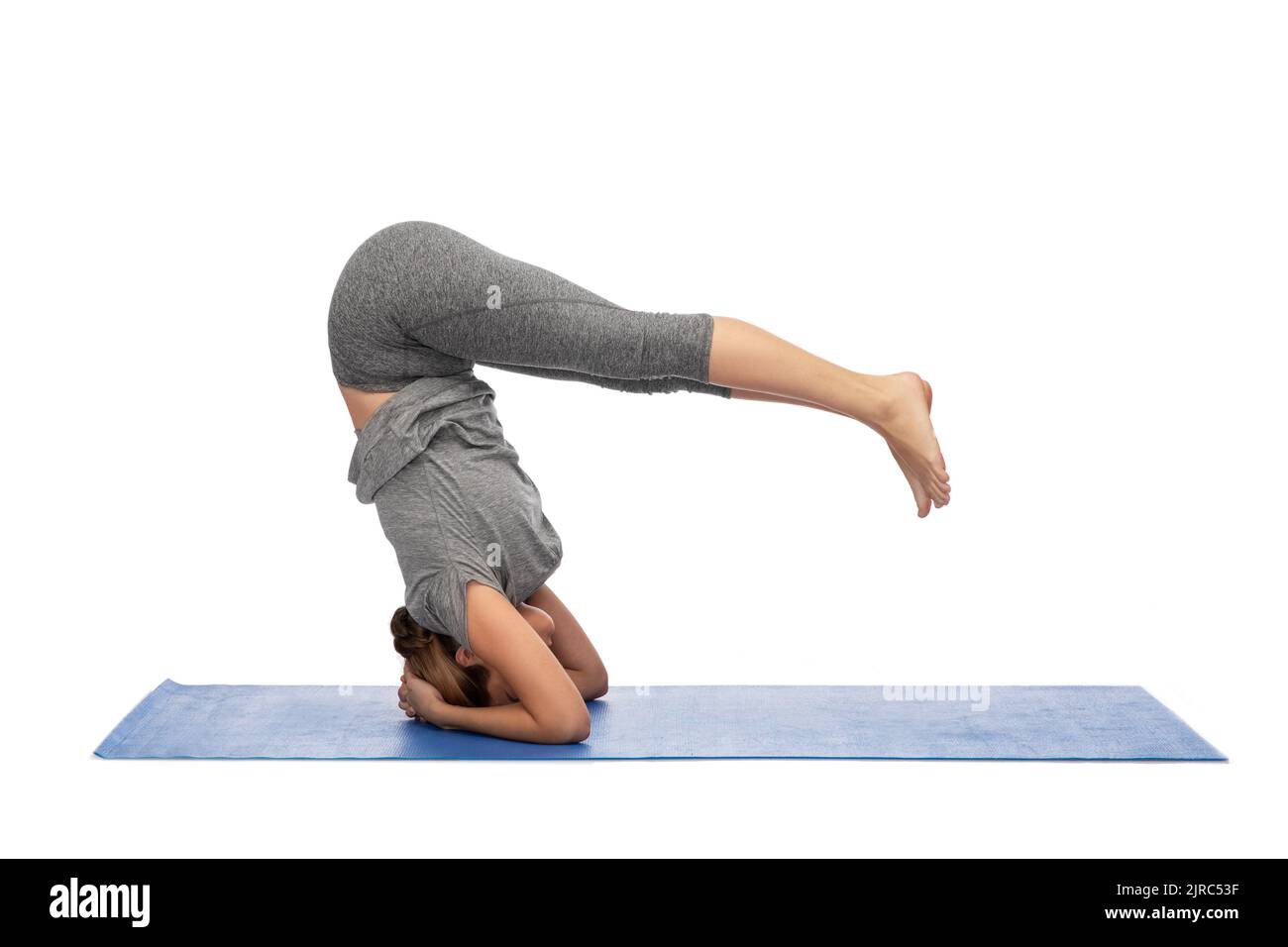Frau macht Yoga im Kopfstand Pose auf Matte Stockfoto