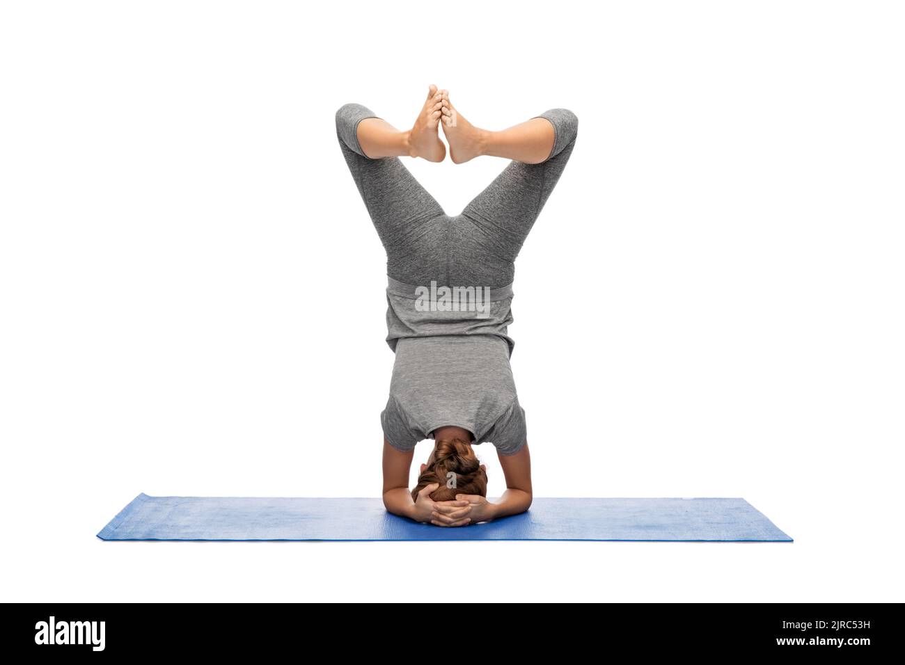 Frau macht Yoga im Kopfstand Pose auf Matte Stockfoto
