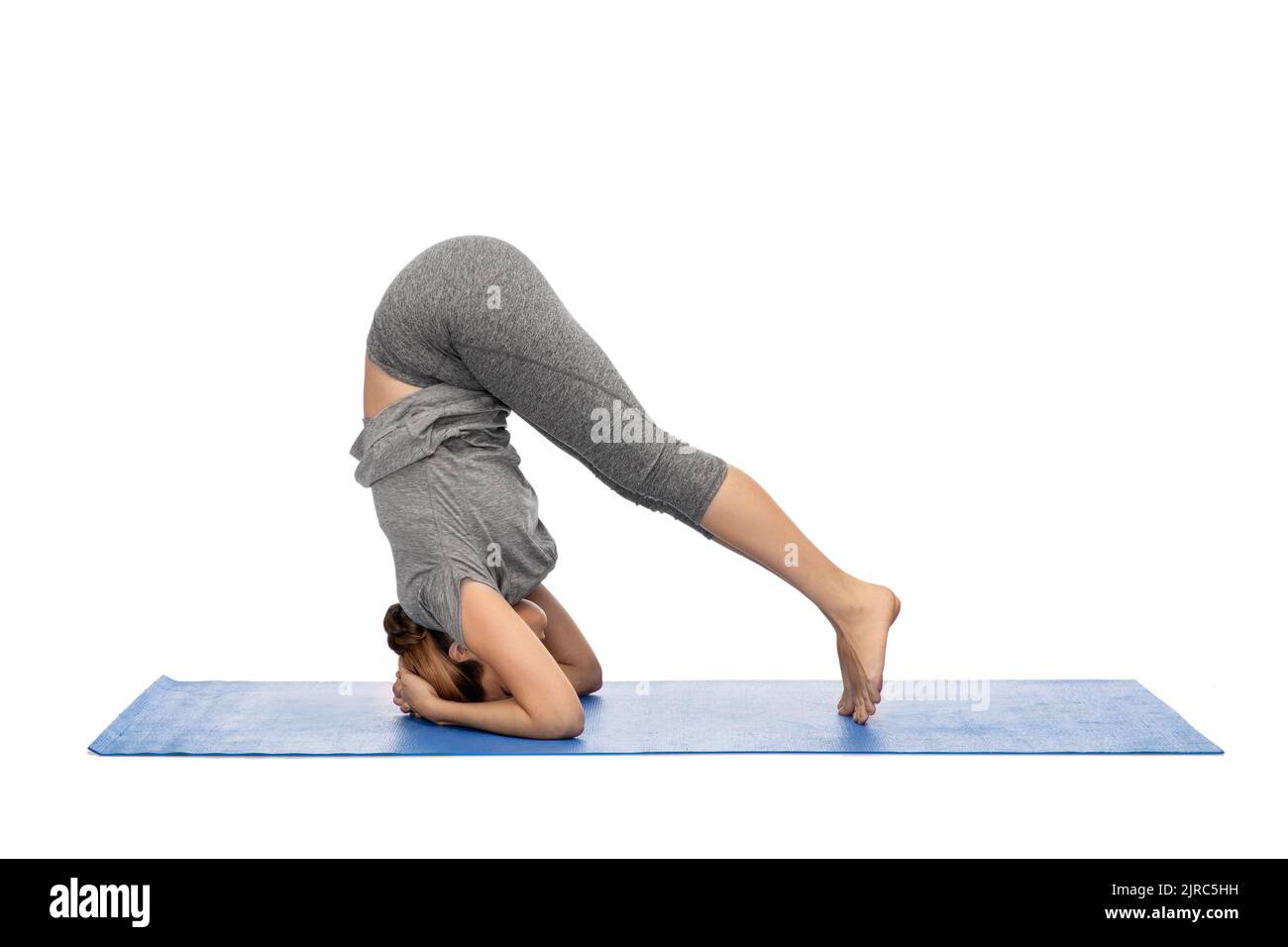 Frau macht Yoga im Kopfstand Pose auf Matte Stockfoto