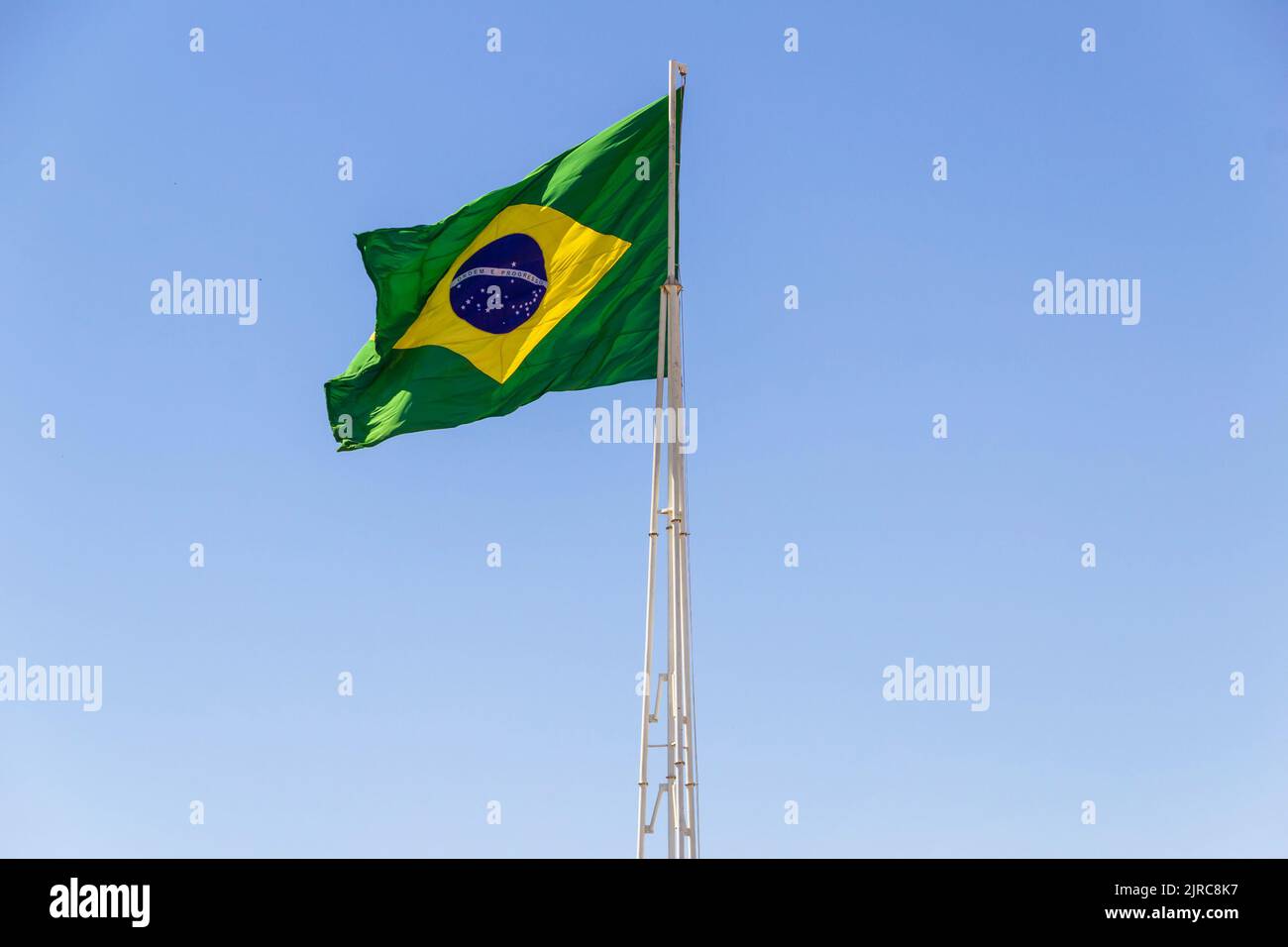 Goiânia, Goias, Brasilien – 23. August 2022: Die Flagge Brasiliens. Die Flagge Brasiliens fliegt, flattert im Wind und der blaue Himmel im Hintergrund. Stockfoto