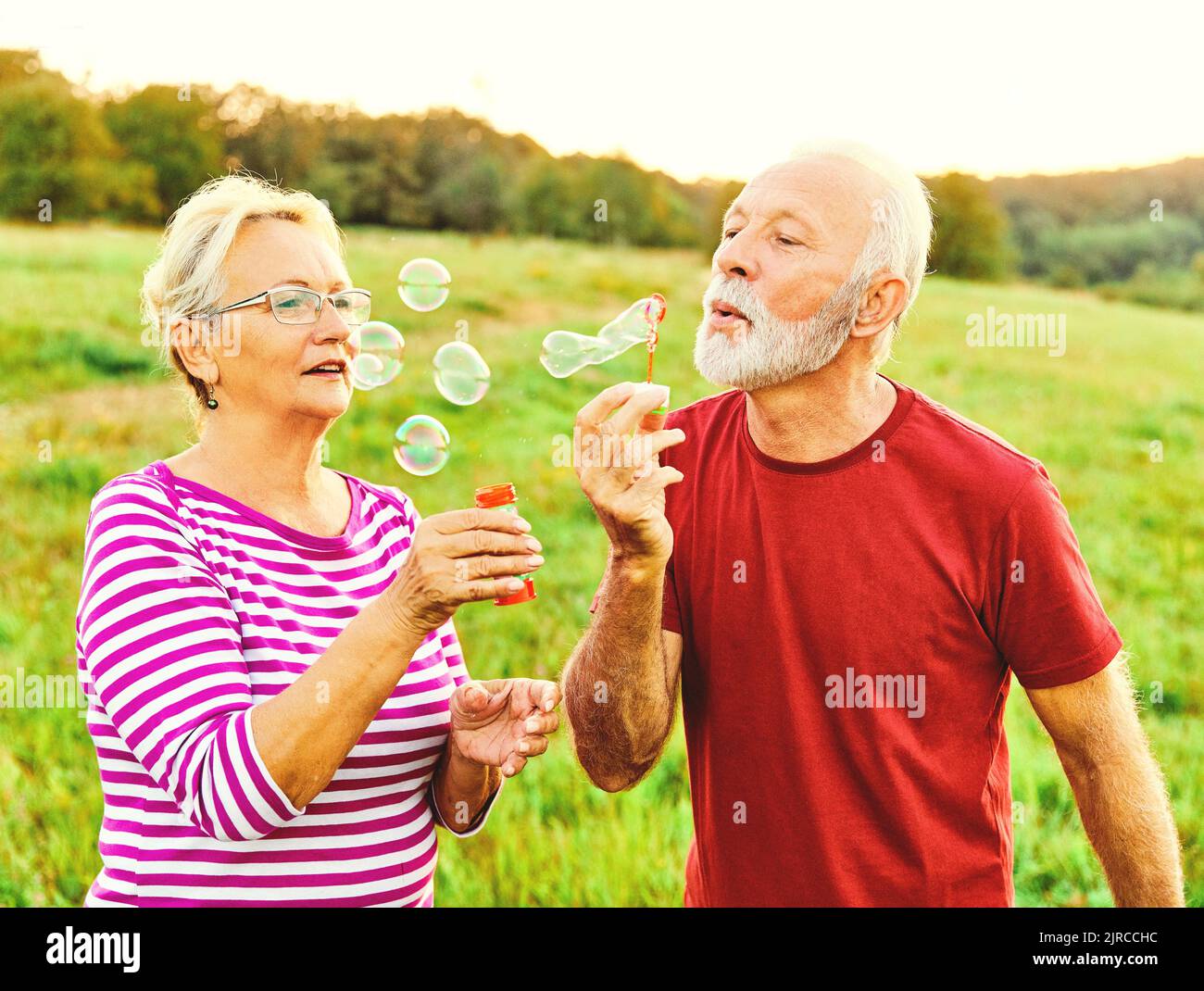 Frau Mann im Freien Senior paar glücklich Spaß Ruhestand zusammen Blase Seife weht Liebe alte Natur reifen Stockfoto