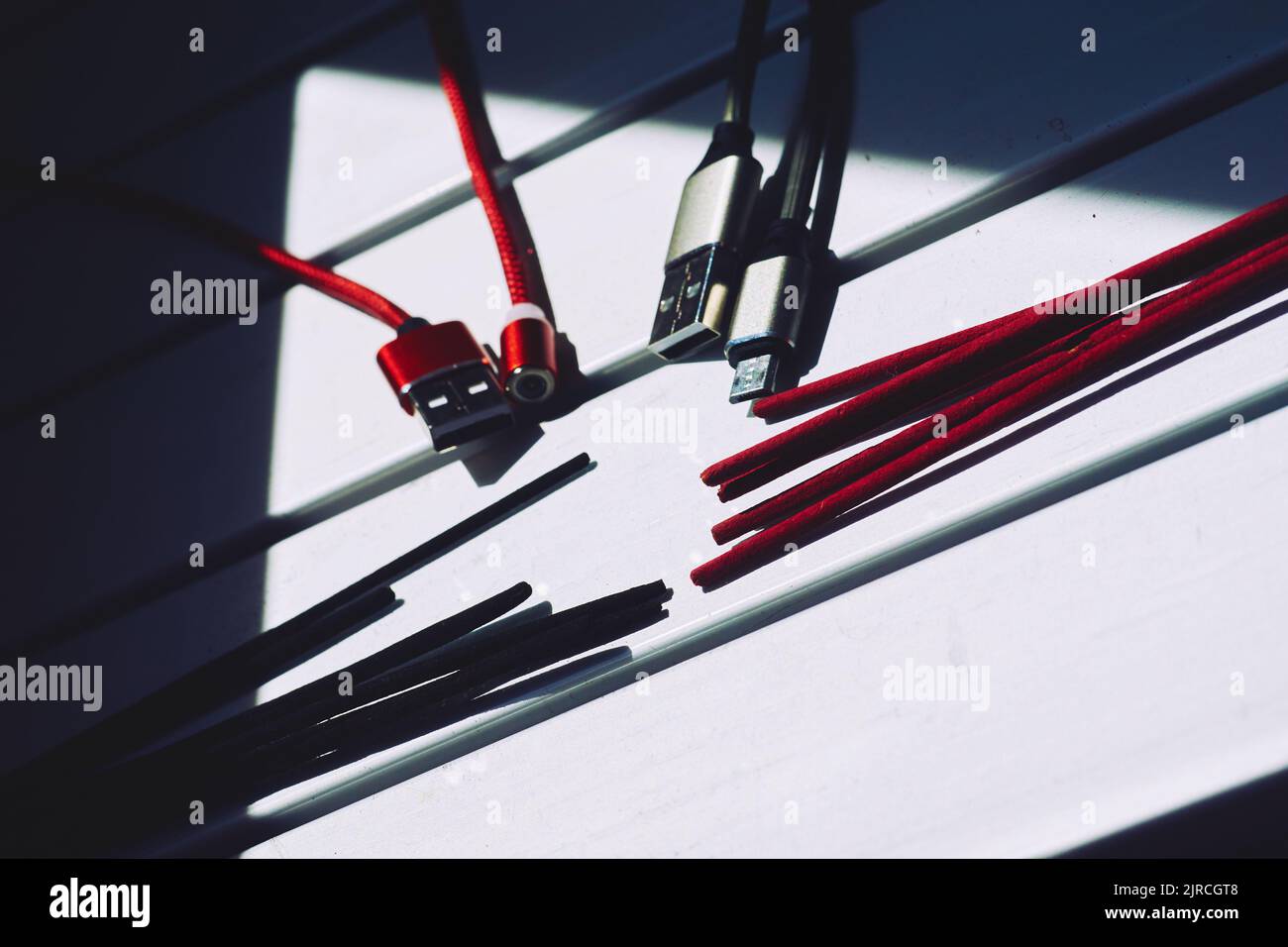 Digitale Meditation. Rot-schwarze usb-Kabel, rot-schwarze Räucherstäbchen. Stockfoto