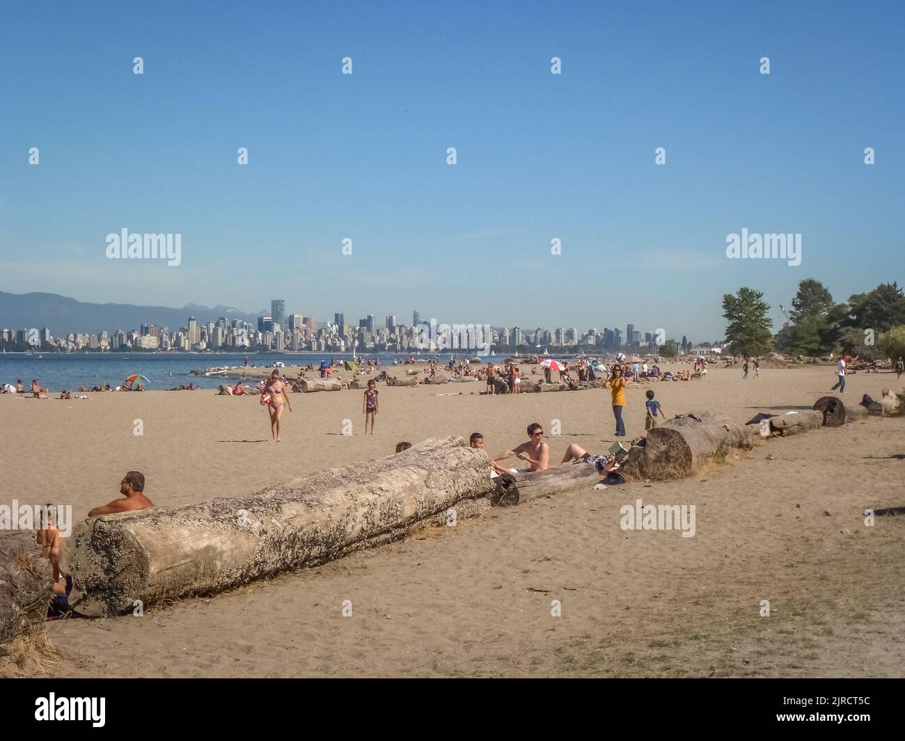 Vancouver, BC, Kanada-5. August 2022: Menschen am städtischen Strand von Kitsilano mit Blick auf die Skyline der Stadt im Hintergrund. Stockfoto
