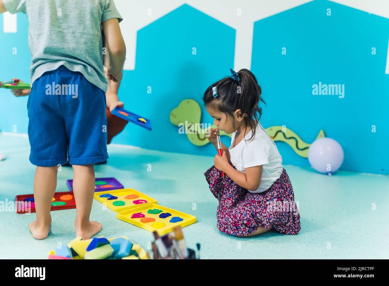 Vorschulkinder, die im Kindergarten mit ihrer Lehrerin mit Farben spielen. Hochwertige Fotos Stockfoto