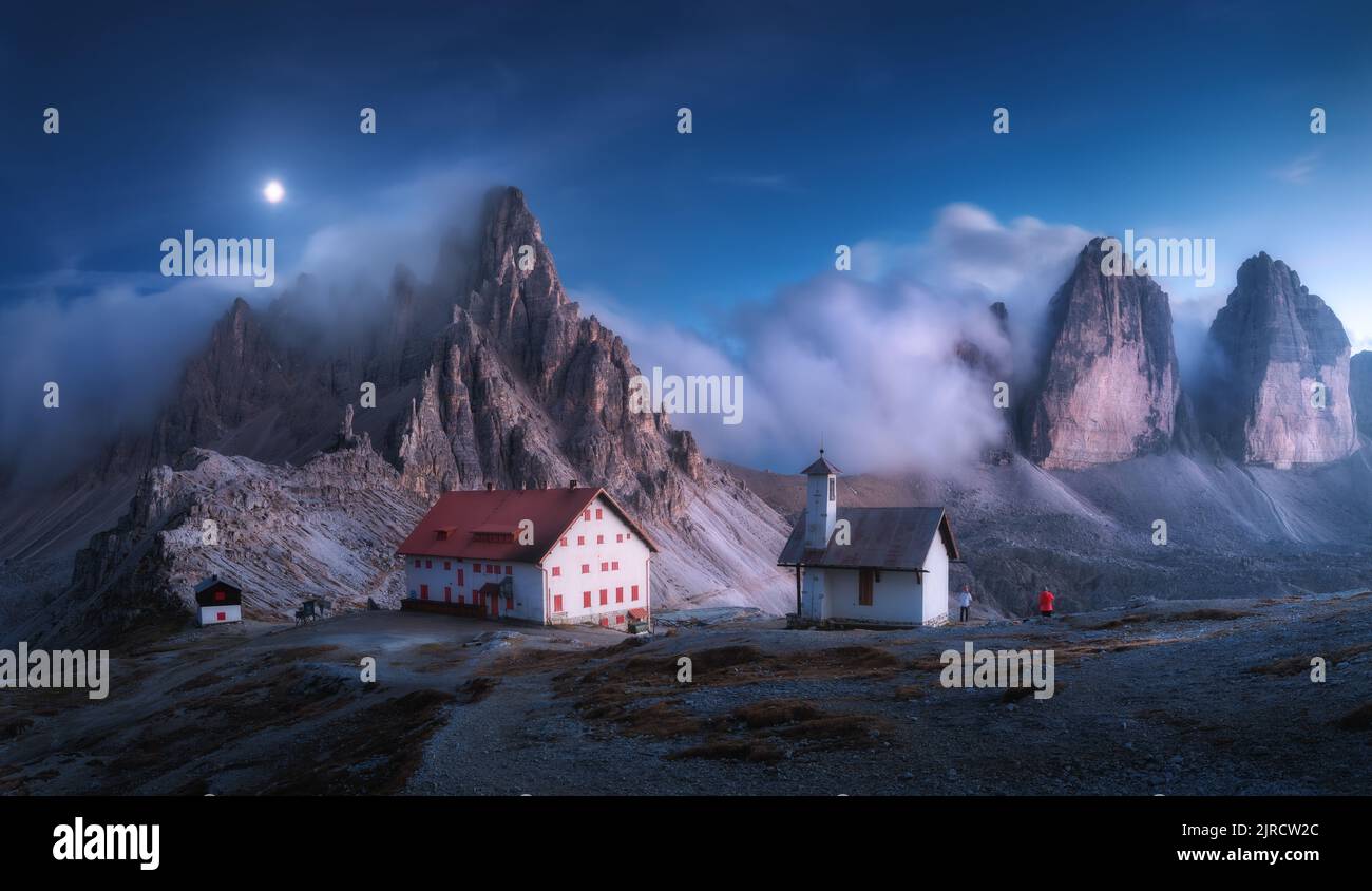 Berge im Nebel mit schönem Haus und Kirche in der Nacht Stockfoto