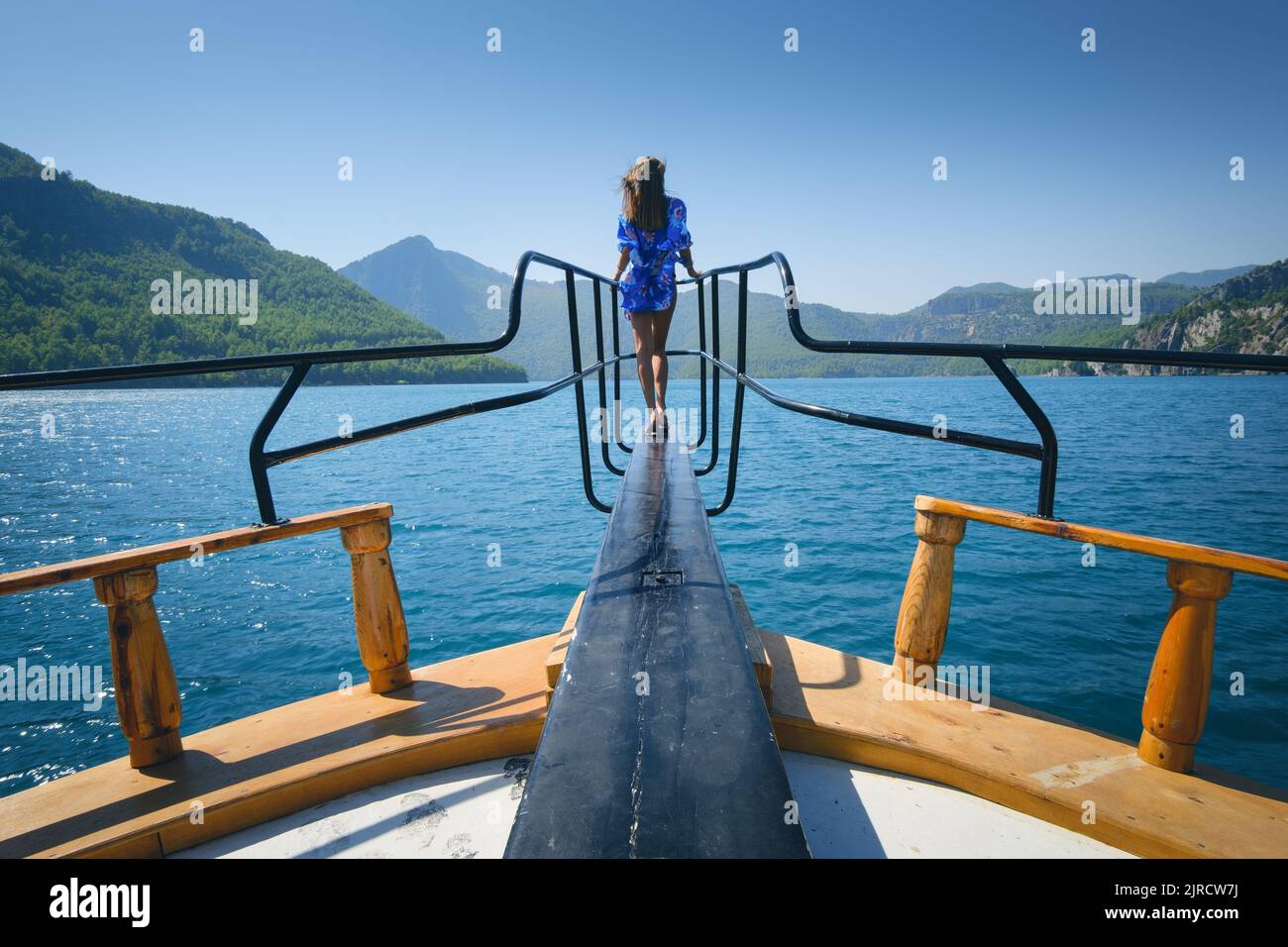 Junge Frau auf der schwimmenden Yacht auf dem Meer bei sonnigem Sonnenschein Stockfoto