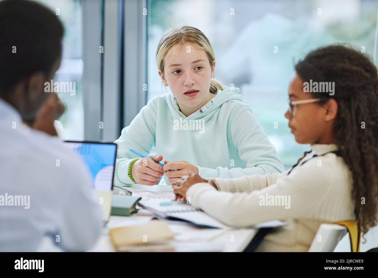 Minimalporträt eines jungen Teenagers, das in der Schule in einer Gruppe aktiv ist und Mitschülern zuhört Stockfoto