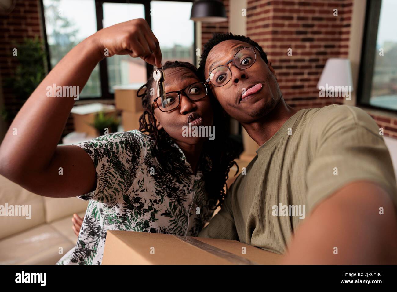 afroamerikanische Partner fühlen sich über neue Immobilien fröhlich, halten die Schlüssel zum Familienhaus und ziehen zusammen. Eigenheimbesitzer feiern Lebensleistung und beginnen neue Anfänge. Stockfoto