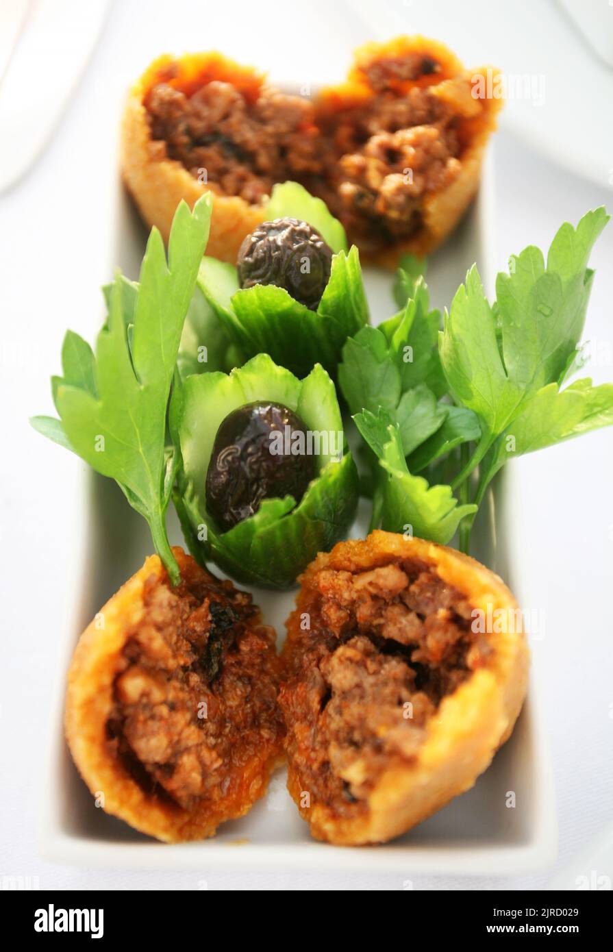 Gefüllte Fleischbällchen (türkisch: Isli Kofte) mit Oliven auf dem Speiseteller. Stockfoto