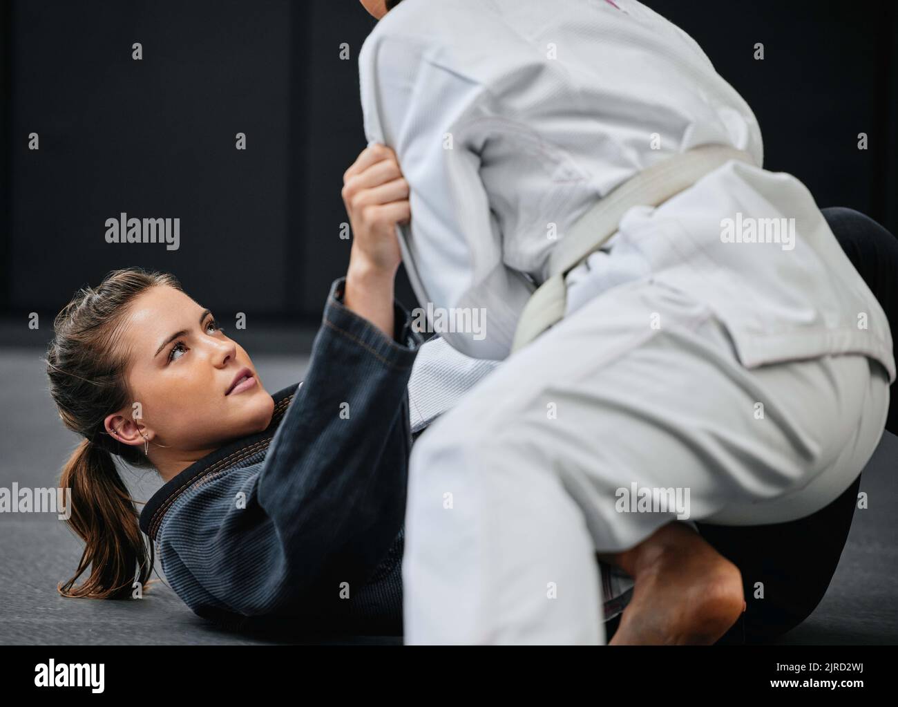 Starkes, weibliches und Kampfsporttraining in einem Übungsstudio mit einem Gegner. Fit, junge und aktive Frau in einer Verteidigung Lektion an einem Dojo Stockfoto