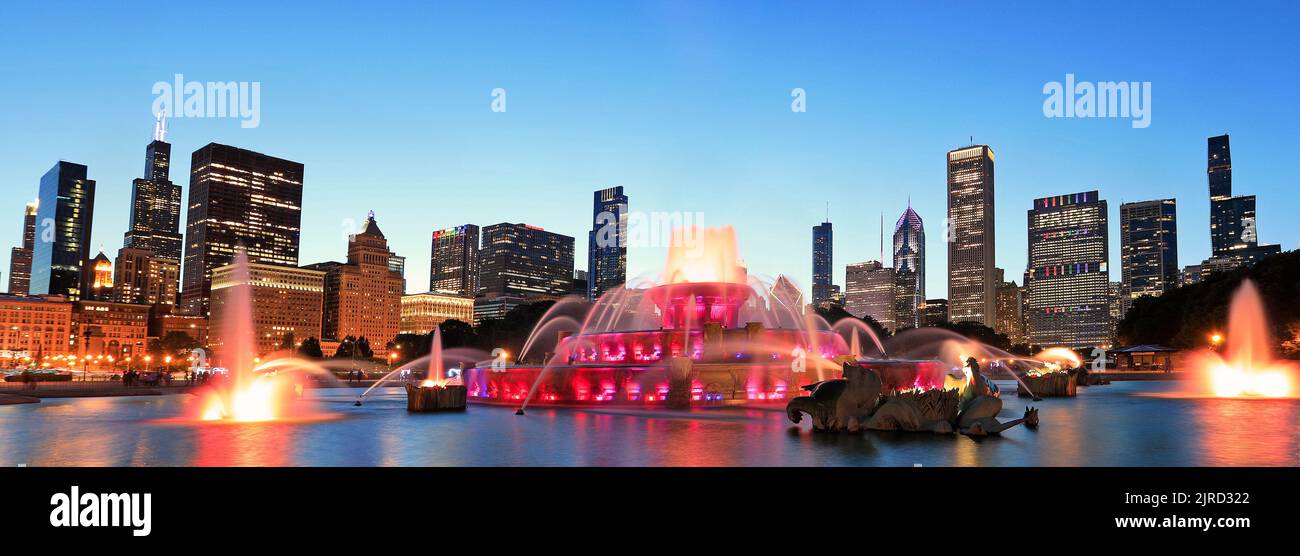 Die Skyline von Chicago wird in der Abenddämmerung mit einem farbenfrohen Buckingham-Brunnen im Vordergrund, Illinois, USA, beleuchtet Stockfoto