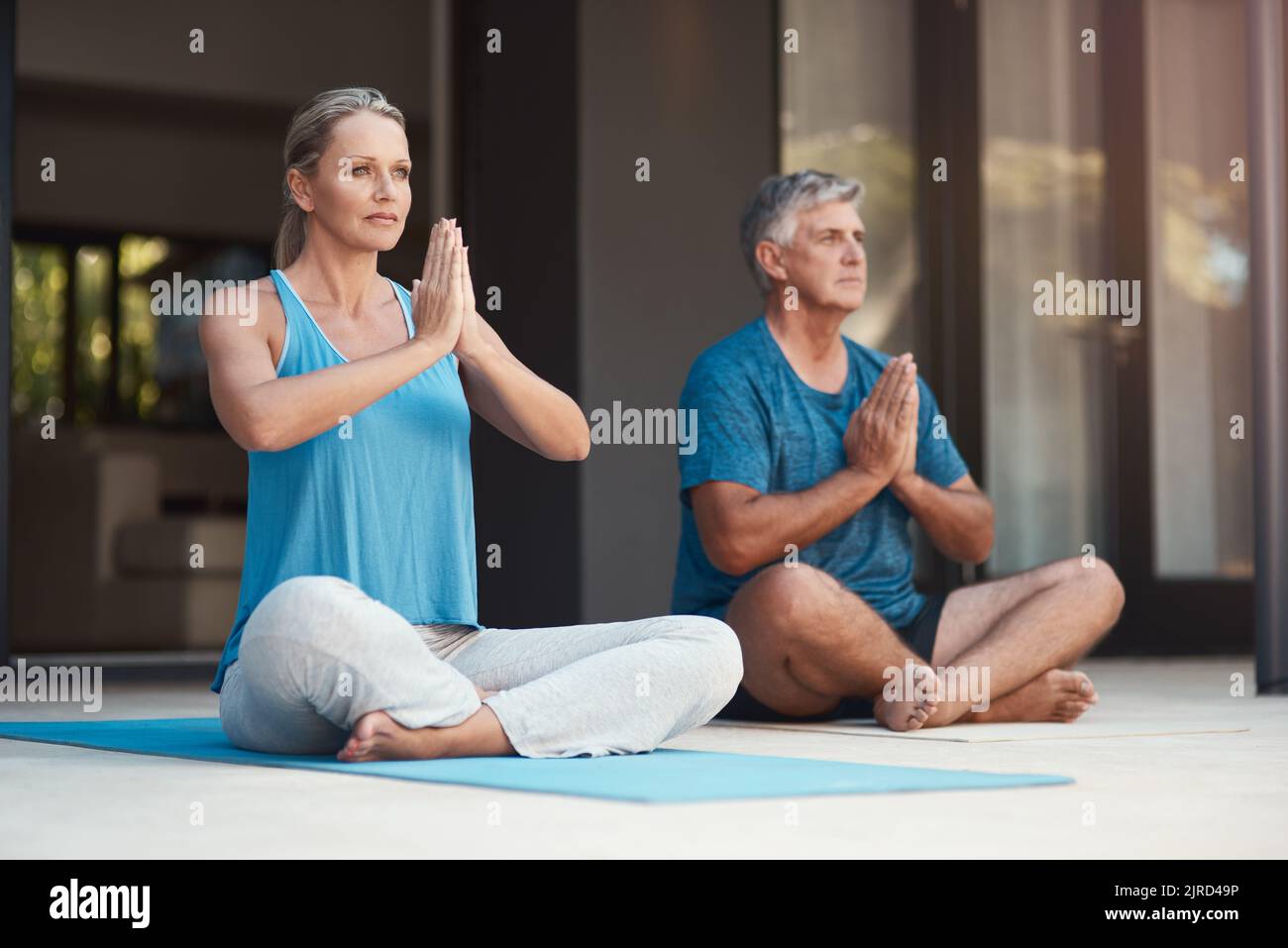Lassen Sie allen Stress los und lassen Sie den Frieden über sich ziehen. Ein reifes Paar nimmt friedlich eine Yoga-Pose mit gekreuzten Beinen und zusammengesteppten Händen ein. Stockfoto