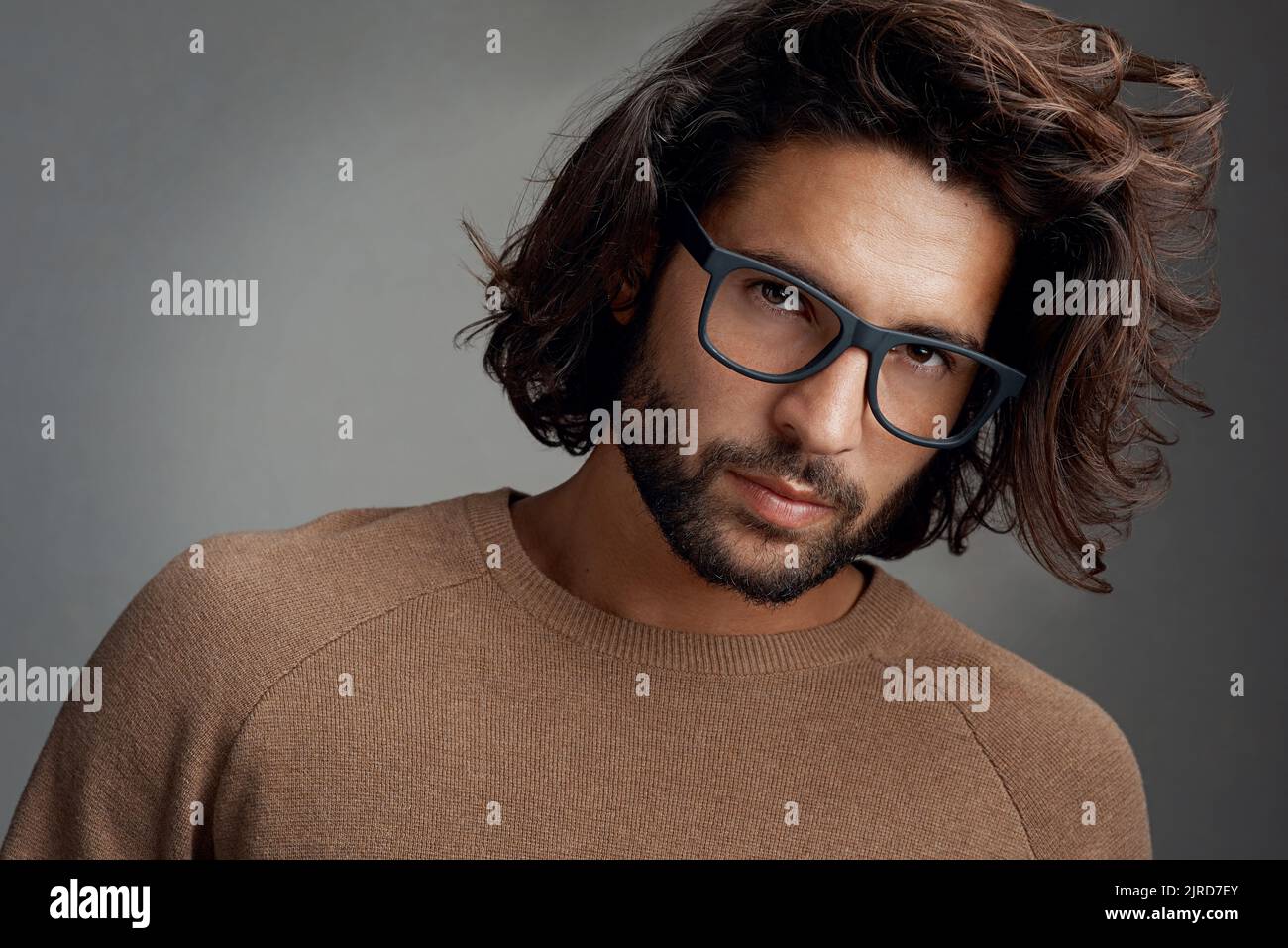 Schickes Design. Studioaufnahme eines hübschen jungen Mannes, der eine Brille vor grauem Hintergrund trägt. Stockfoto