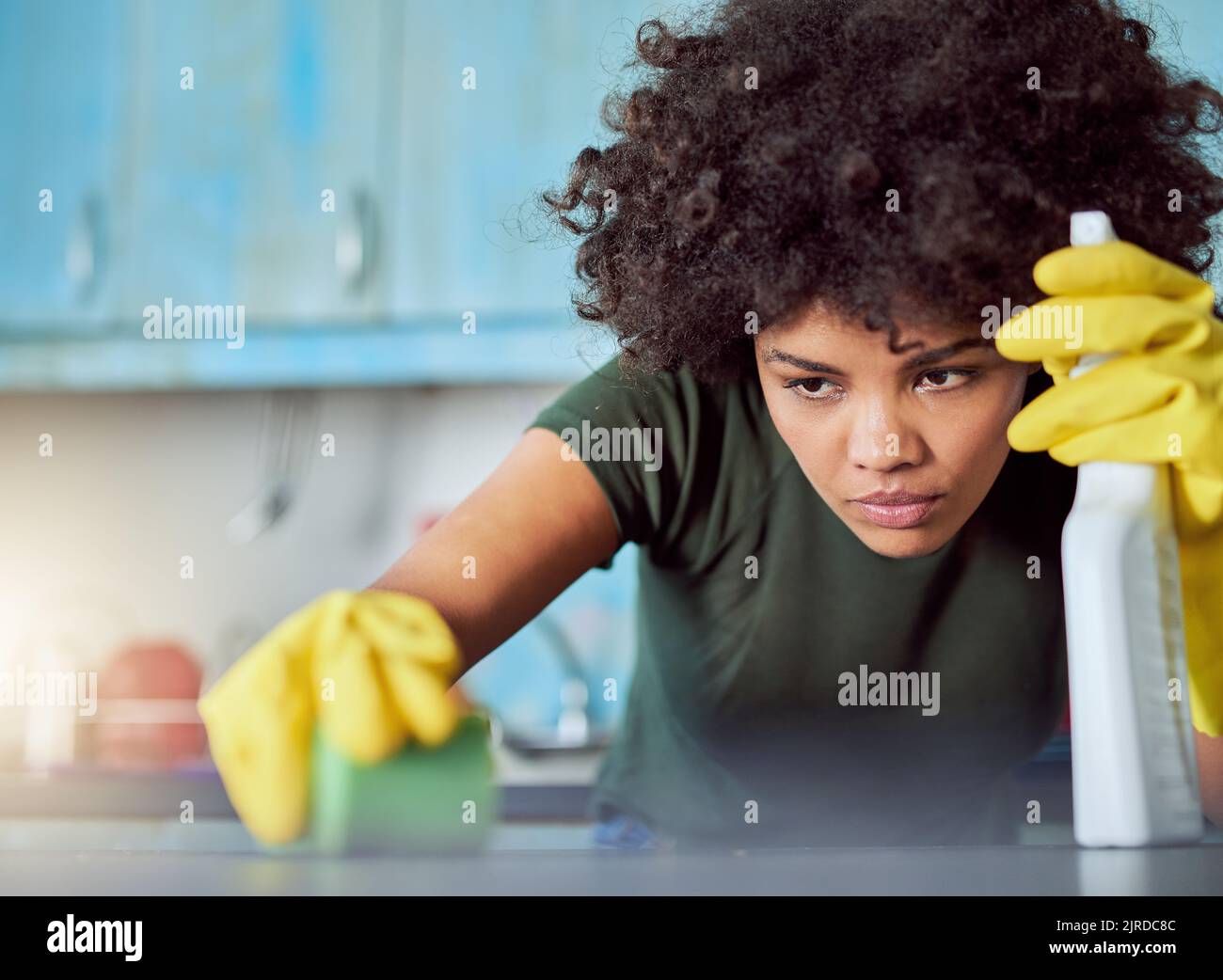 Es braucht Konzentration, um Flecken zu entfernen. Eine attraktive junge Frau mit gelben Handschuhen, die ihr Zuhause putzt. Stockfoto