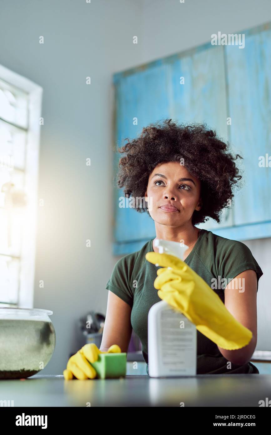 Ich bin fast fertig. Eine attraktive junge Frau mit gelben Handschuhen, die ihr Zuhause putzt. Stockfoto