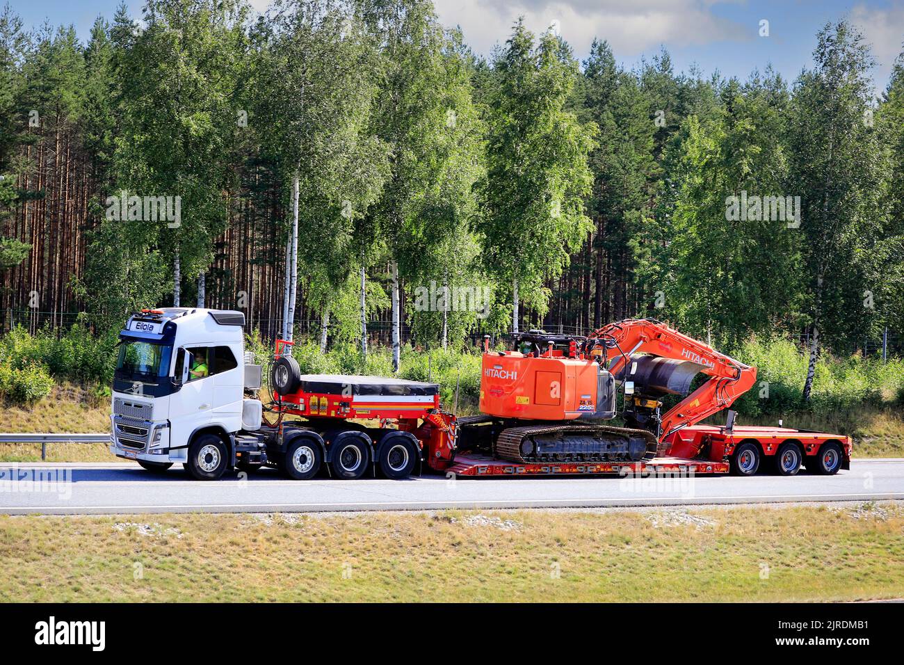 Weißer Volvo FH16 LKW von Eilola Logistics Oy zieht Hitachi Zaxis 225 Bagger auf dem Tieflader-Anhänger von FYMONville auf der Straße. Salo, Finnland. 17. Juli 20. Stockfoto