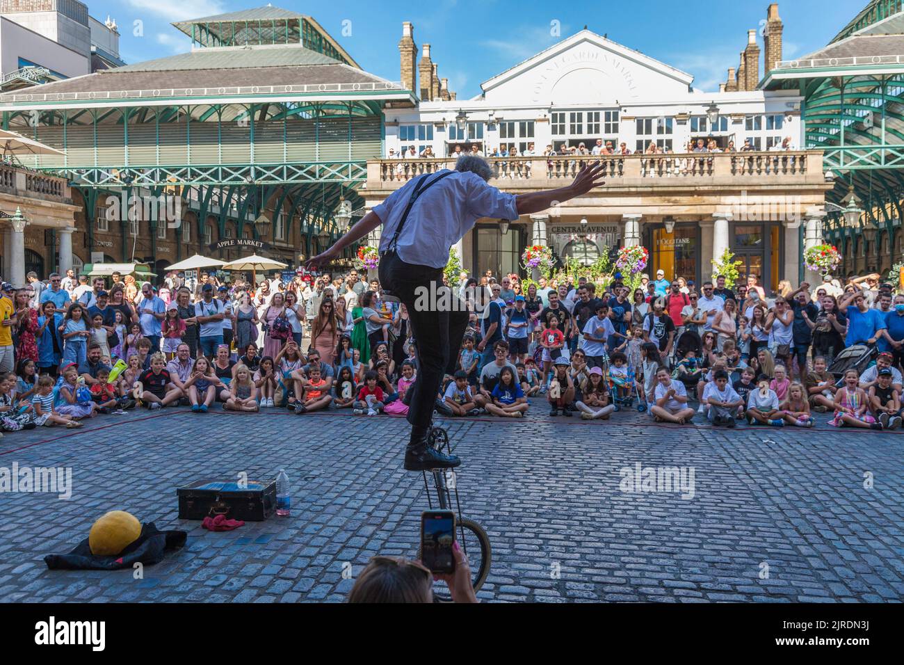 Ein männlicher Jongleur, der Massen auf einem Einrad in Covent Garden, London, England, Großbritannien unterhält Stockfoto