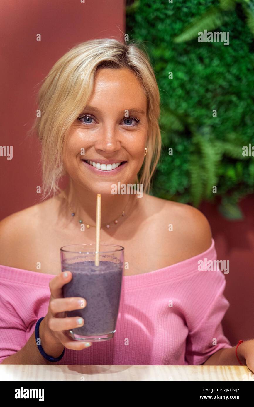 Frau lächelt, während sie in einem Café einen Smoothie trinkt. Gesundes Lifestyle-Konzept. Stockfoto