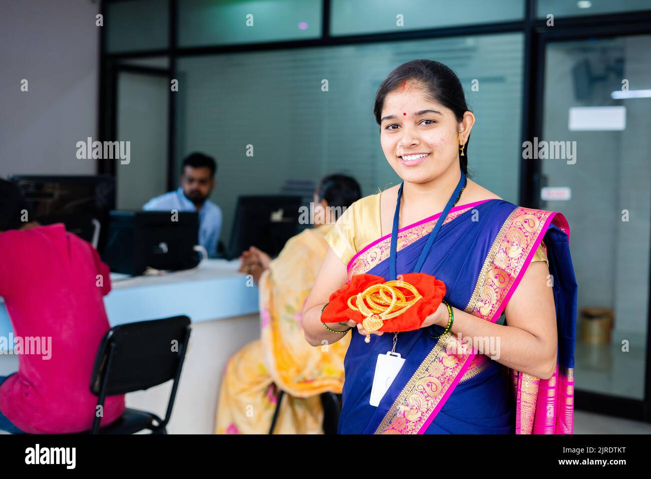 Glücklich lächelnde Frau bei der Bank mit Goldschmuck in der Hand Blick Kamera bei der Bank - Konzept der Golddarlehen, Finanz-oder Bankservice und Investitionspläne Stockfoto
